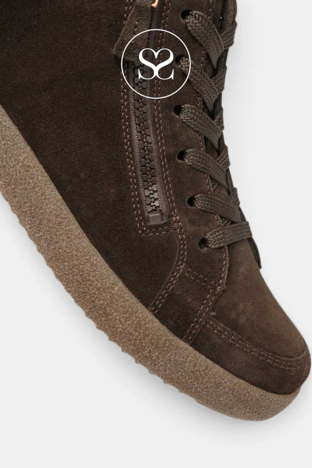 A close-up of a dark brown suede high-top sneaker boot with matching laces, a side zipper, and a thick textured sole, shown on a light gray background with a circular 'SC' logo overlay.