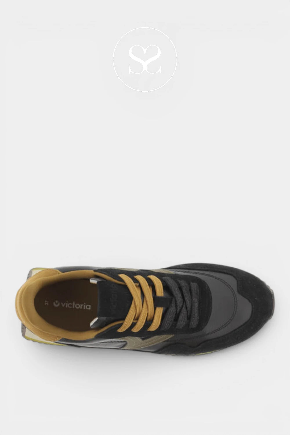 A top-down view of a black and gray sneaker with mustard yellow laces and a tan interior lining, shown on a light gray background with a faint circular logo above.