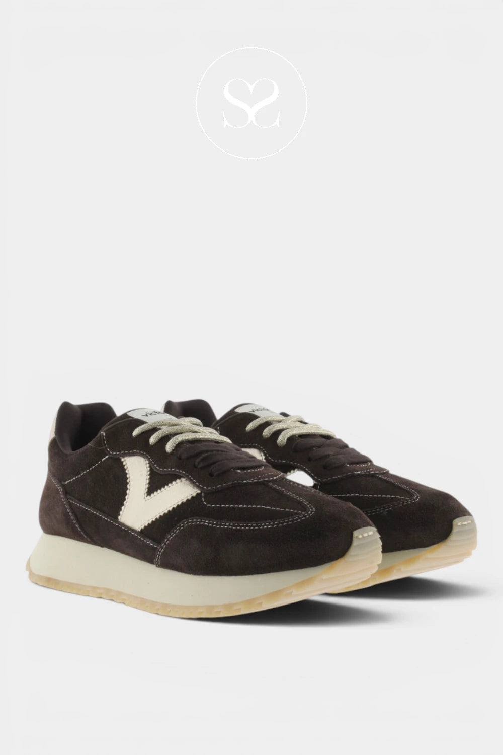 A pair of dark brown suede sneakers with off-white accents, including the laces, logo, and midsole, displayed on a light gray background.