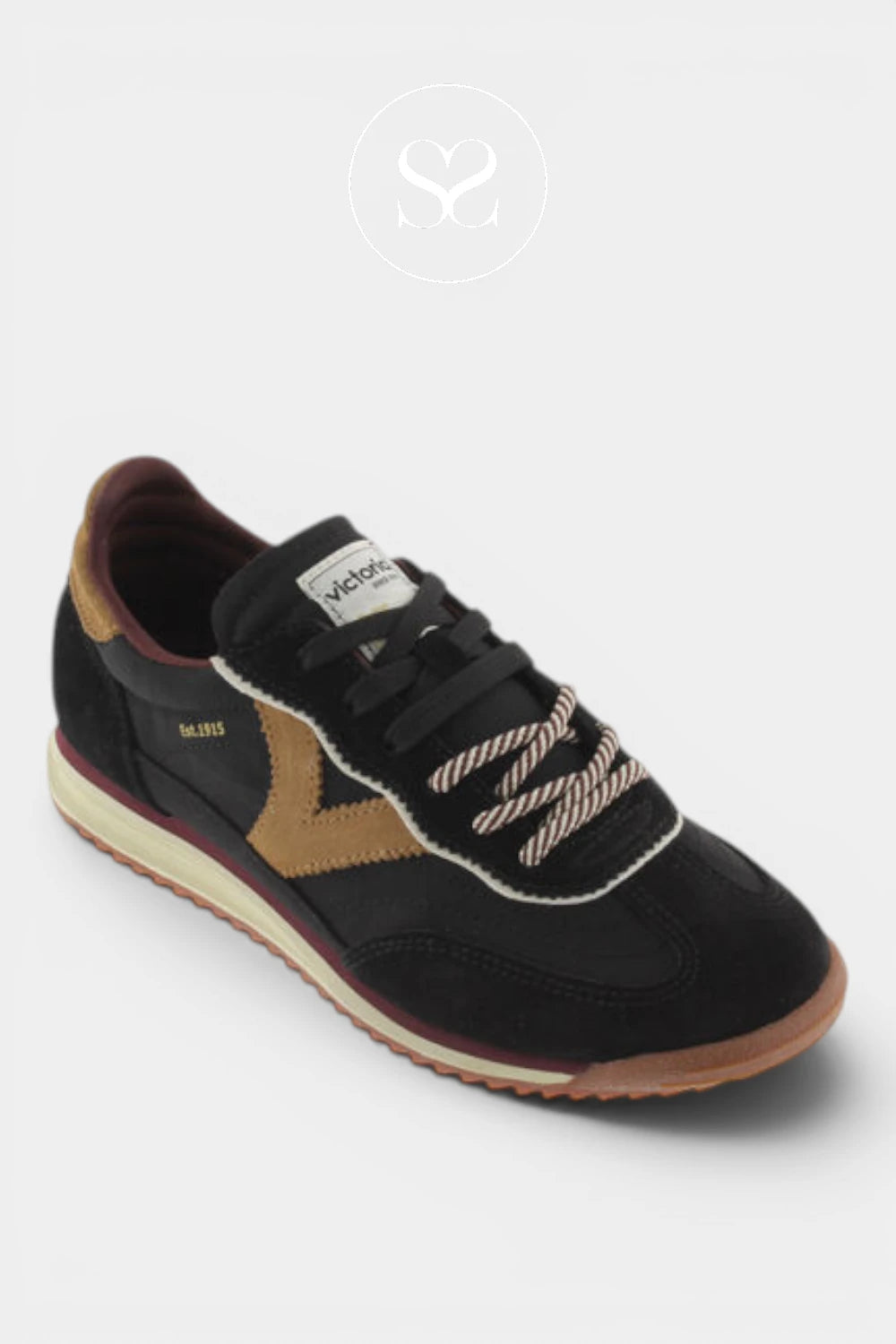 A black low-top sneaker by Vionnet, featuring a tan suede chevron on the side, cream rope laces, and a tan outsole, shown on a light gray background.