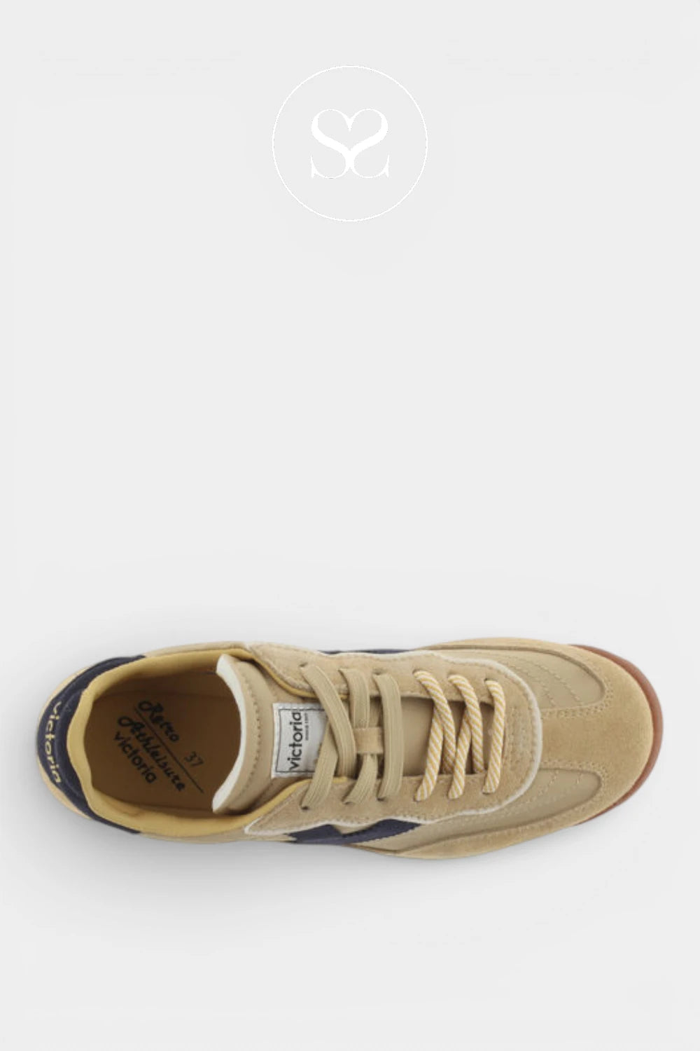 A top-down view of a beige suede and leather low-top sneaker by Michael Kors, featuring beige laces, a dark navy heel tab, and a brown gum outsole, set against a light gray background.