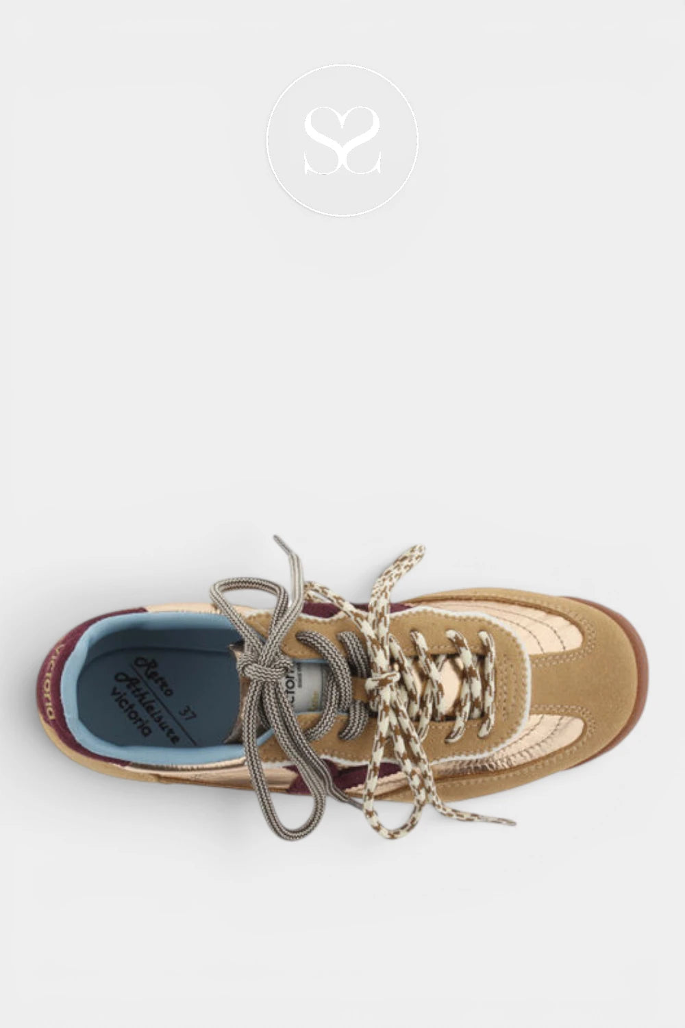 A top-down view of a beige and brown suede sneaker with chunky metallic silver laces, set against a light gray background with a faint watermark logo at the top.