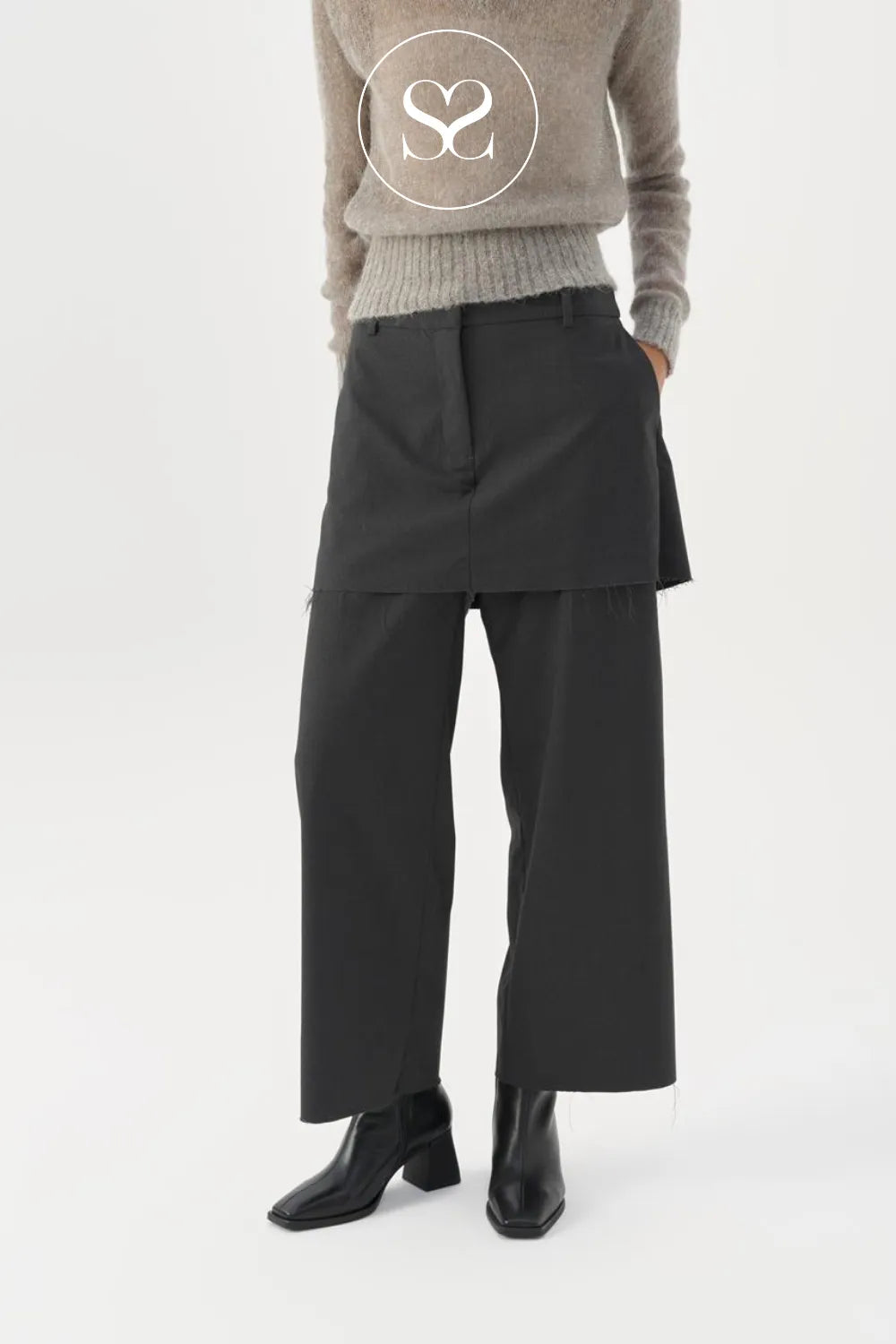 Person wearing a beige sweater, black skirt, and black Vagabond boots on a white background