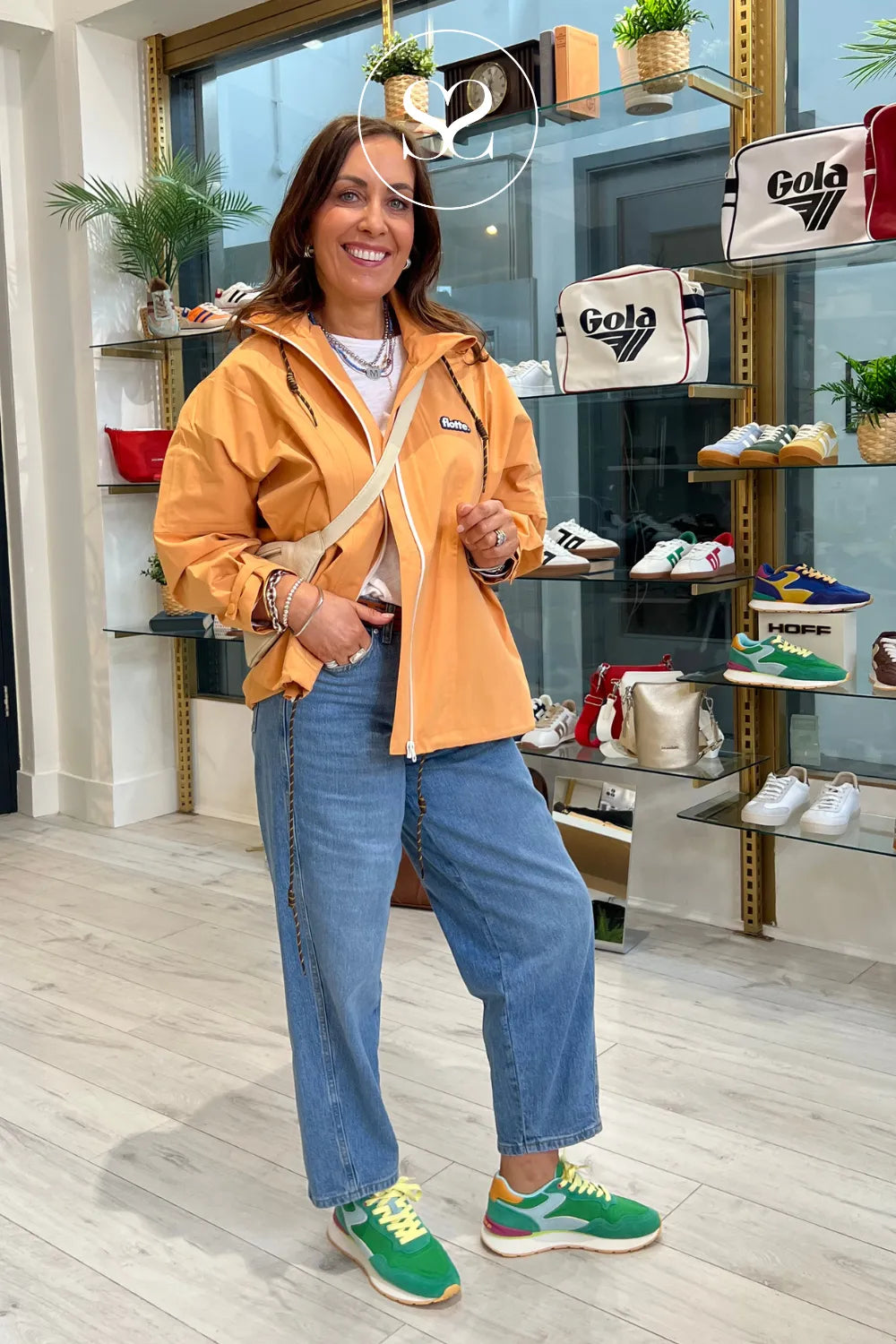 Woman wearing chunky green sneakers from Spanish brand hoff paired with an orange flotte rain jacket