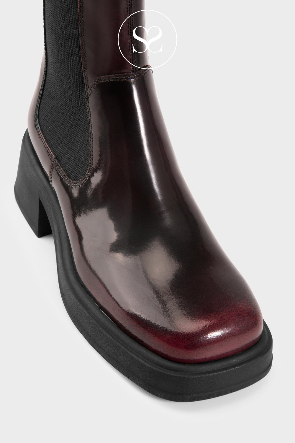 Shiny burgundy boot with a block heel on a light grey background