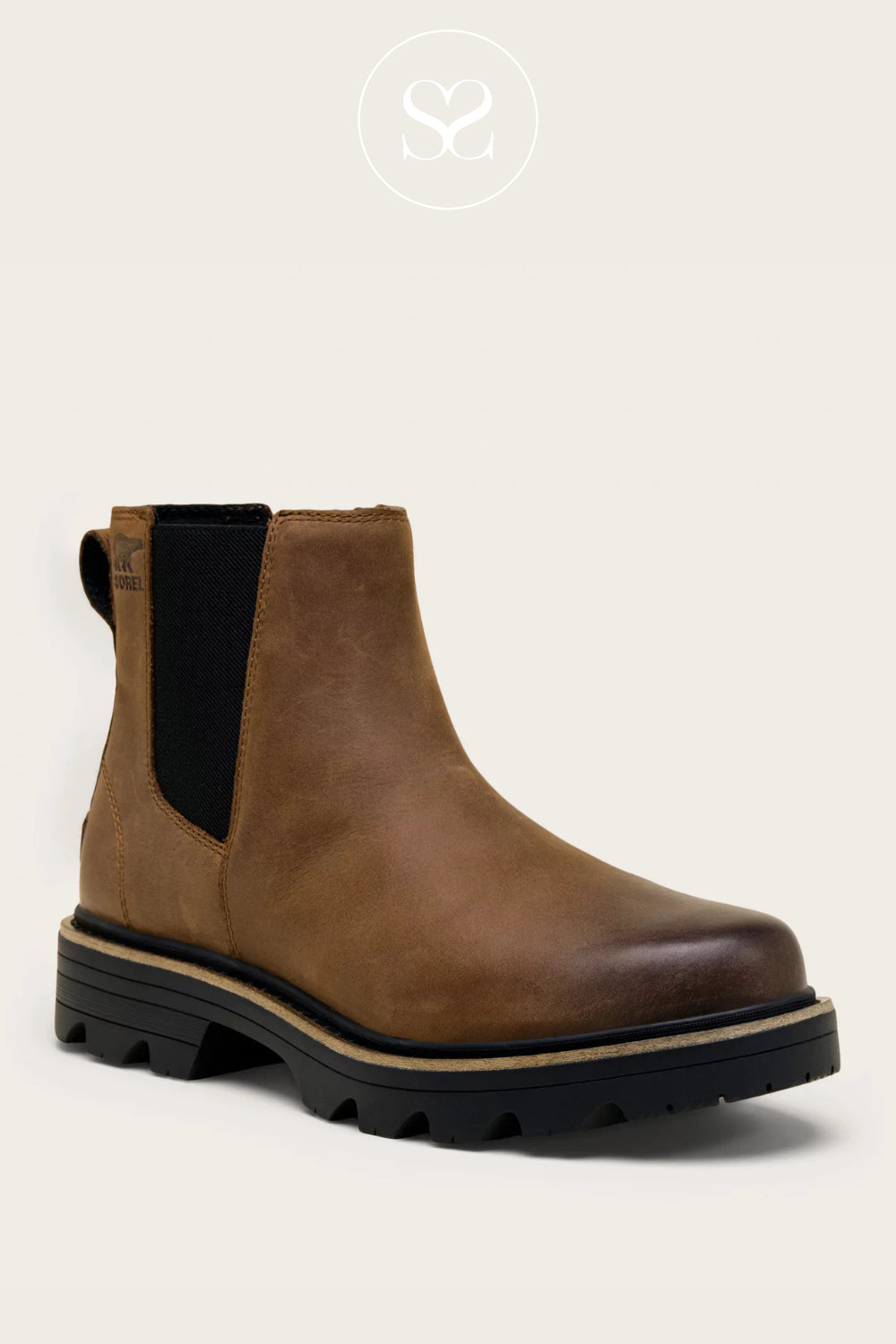 Brown Chelsea boot with black sole on a light beige background