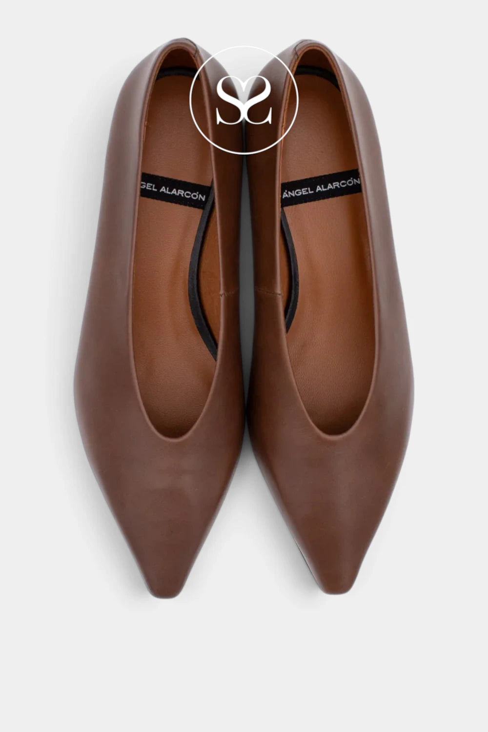 A pair of pointed-toe flats in smooth brown leather, shown from a top-down view on a light gray background. The brand name 'Angel Alarcón' is visible on the black insole labels.
