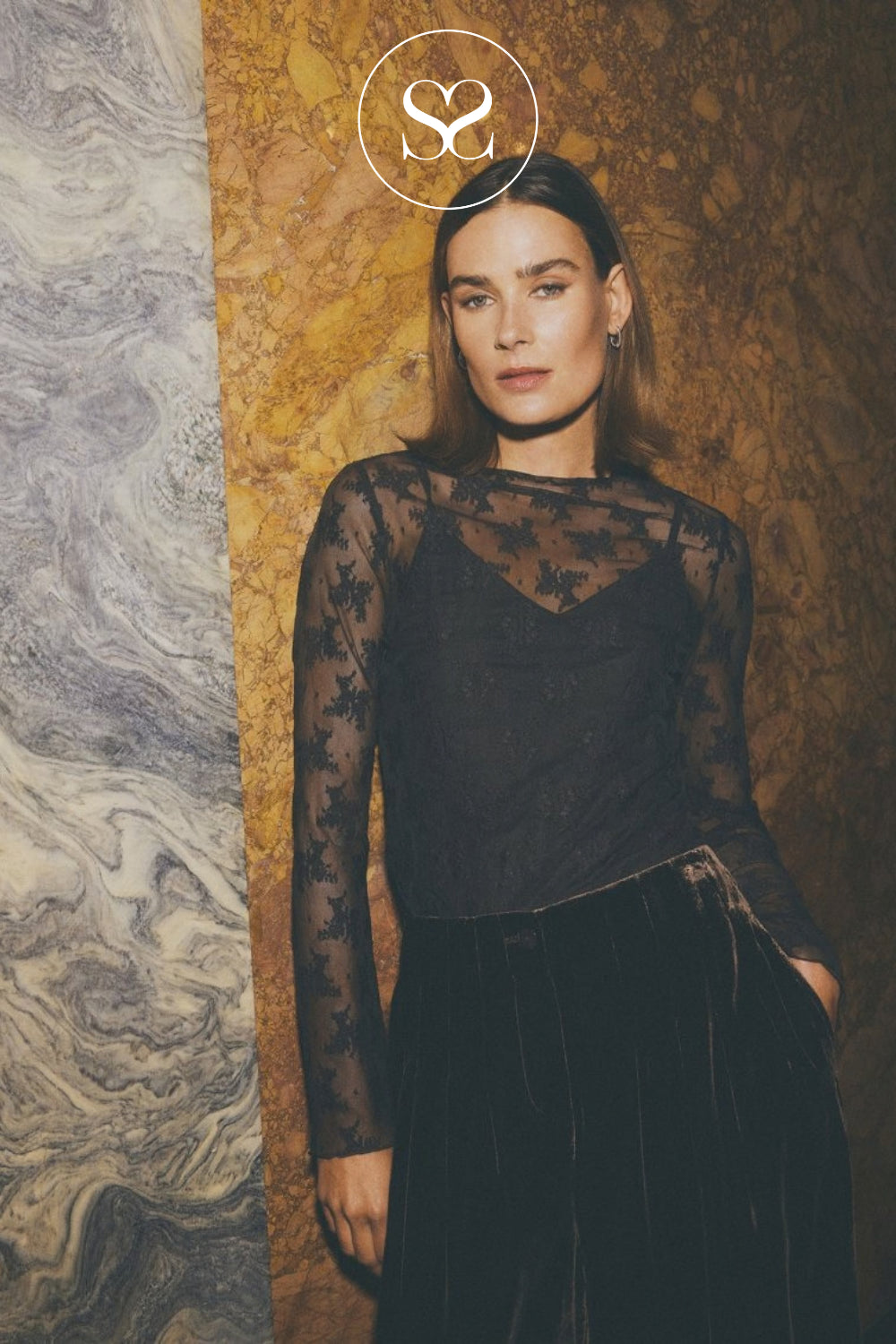 A woman wearing a brown sheer lace long-sleeve top and a black velvet skirt Editorial image for MSCH Copenhagen lace top