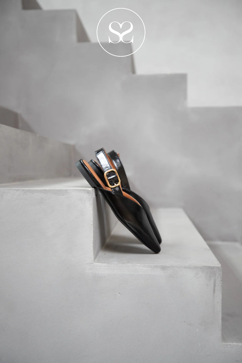 Black flat slingback with a gold buckle