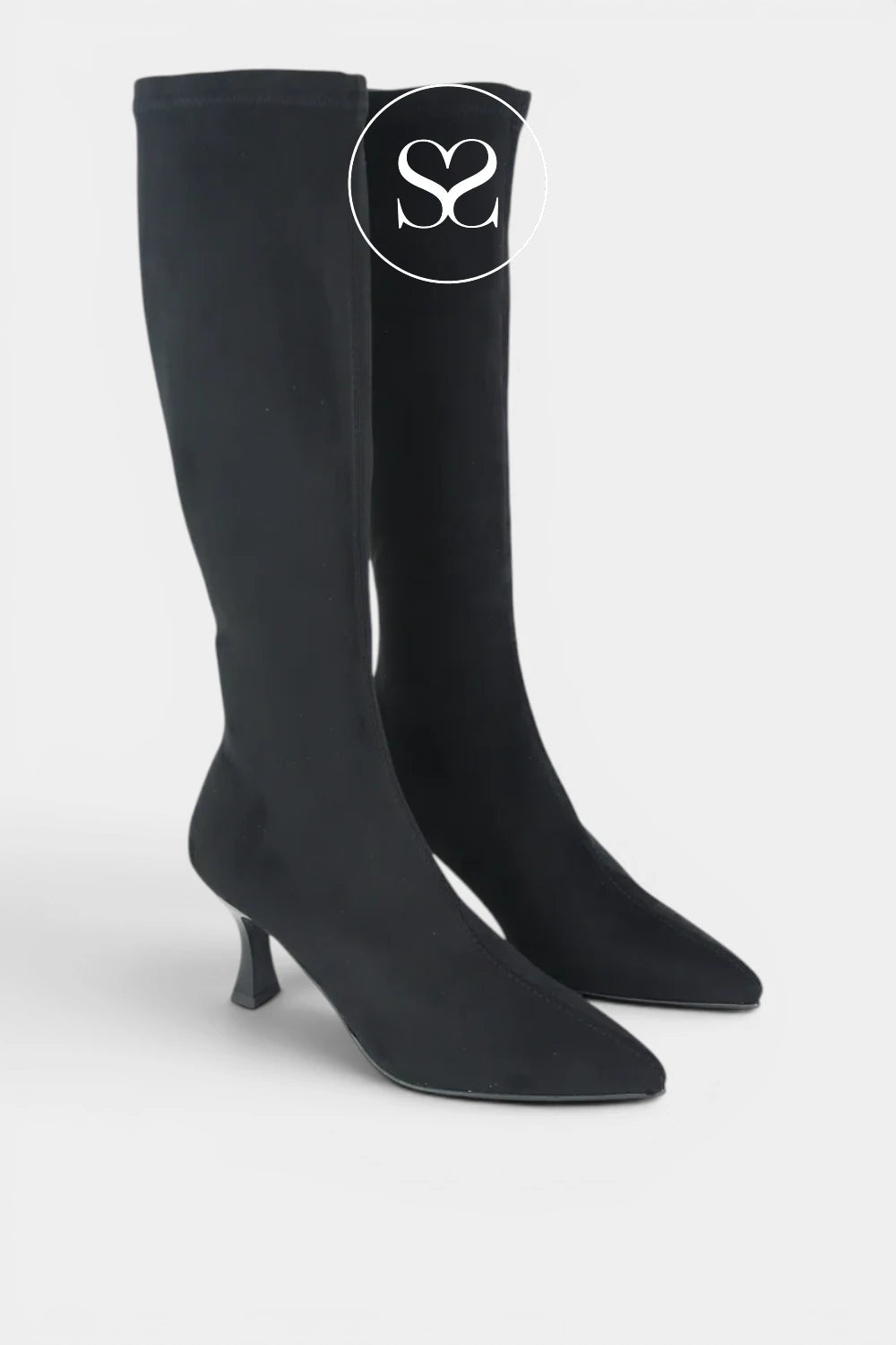 A pair of black suede knee-high boots with a pointed toe and a short kitten heel rom Miss elastic, shown against a light grey background. A white circular logo overlay with the logo 'Sheneil Shoes' positioned near the top of the boot.