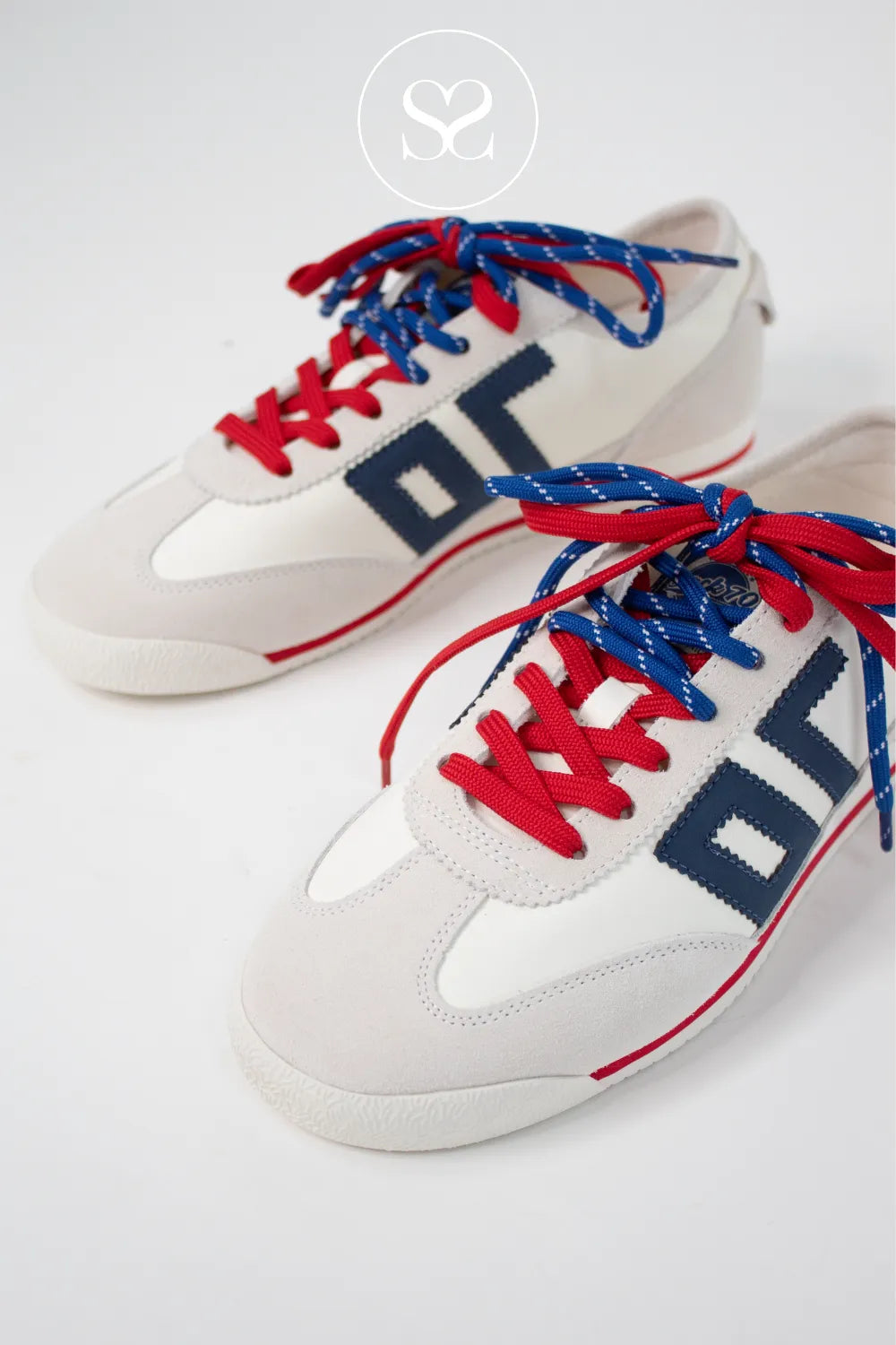 White sneakers with red and blue laces. Flat trainers with soft leather and comfortable sole.