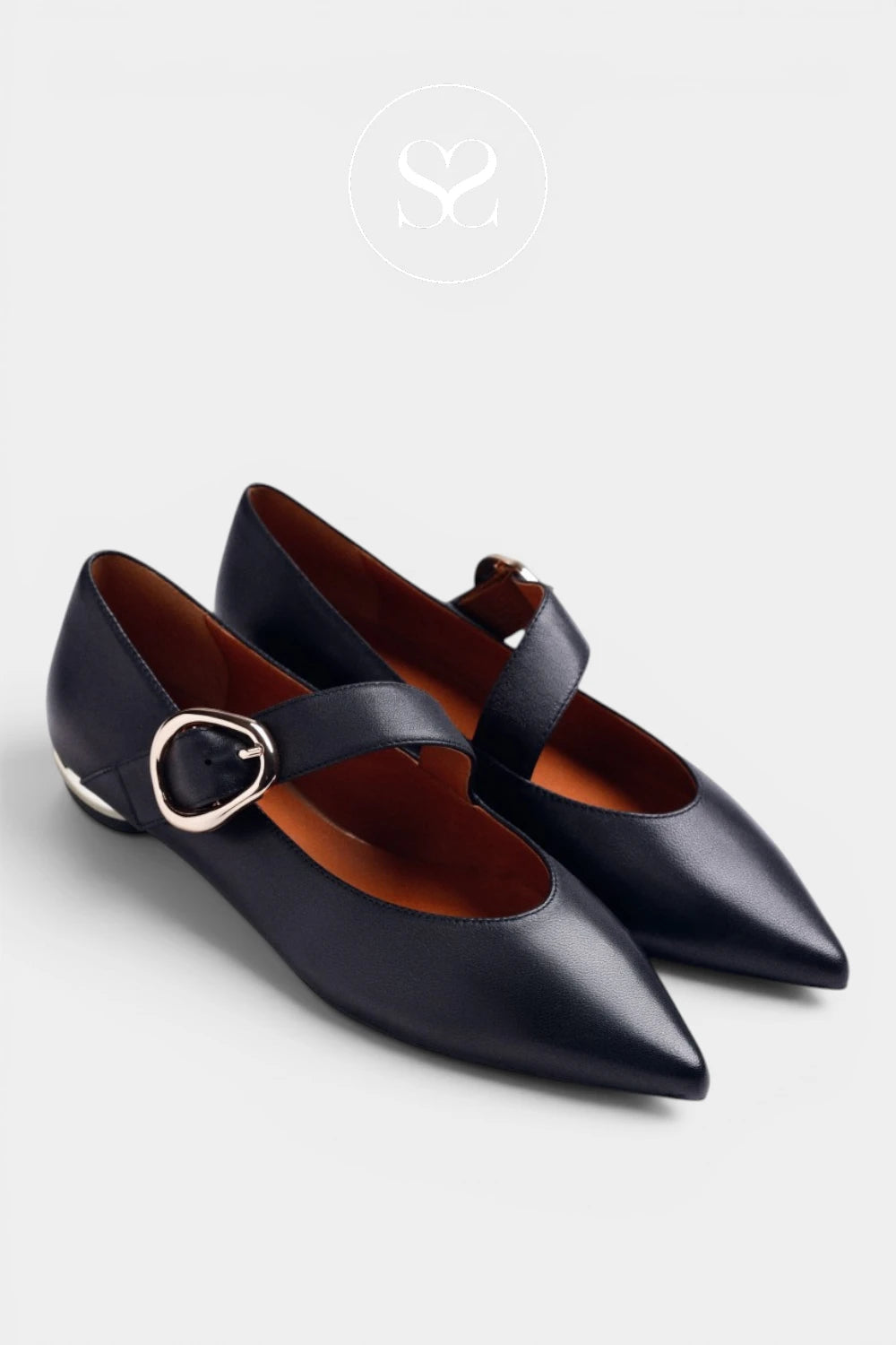 A pair of black leather pointed-toe flats with a single strap across the instep and a silver-tone circular buckle, shown on a light gray background.