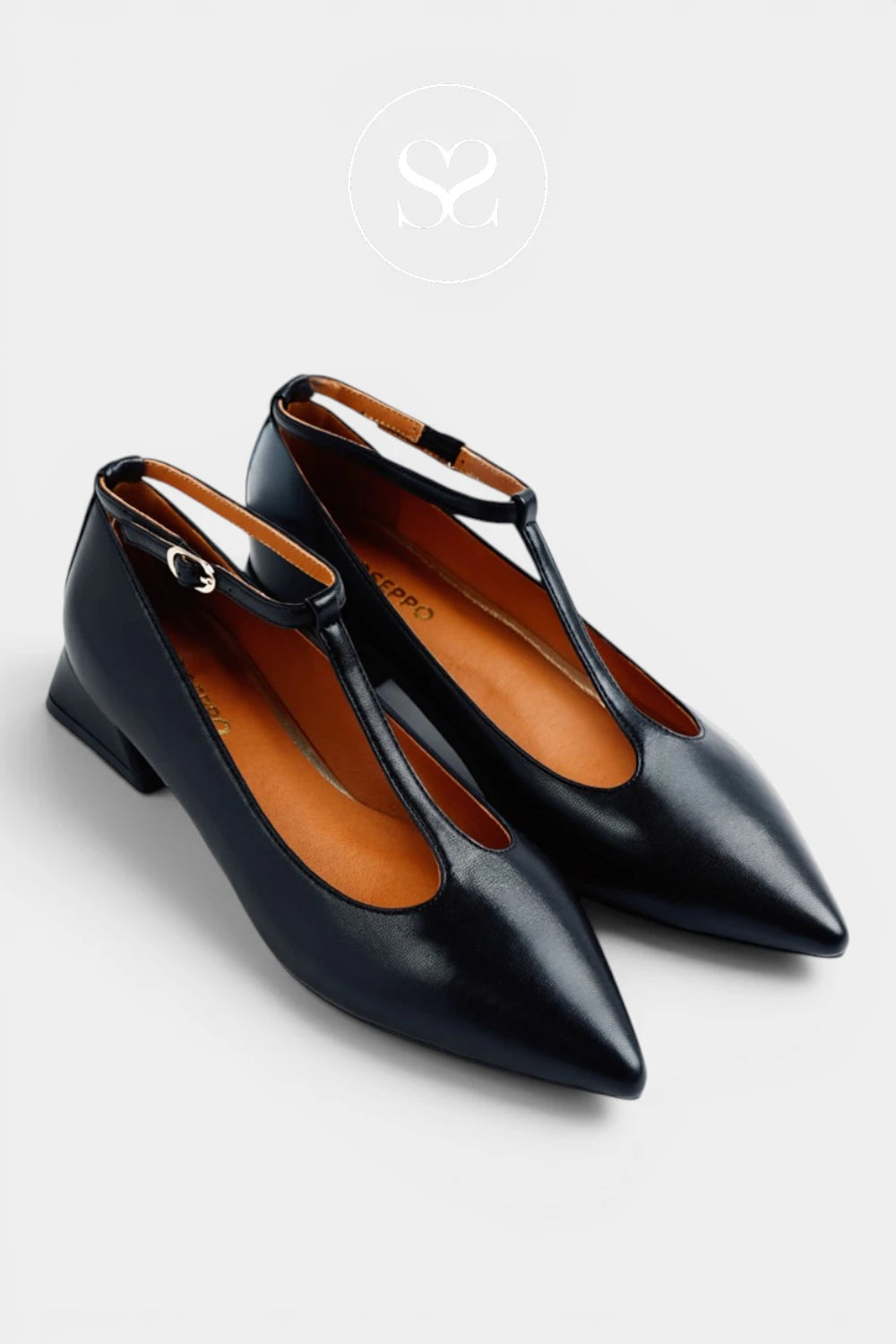 A pair of black leather pointed-toe flats with low block heels and a thin ankle strap, shown on a light gray background.