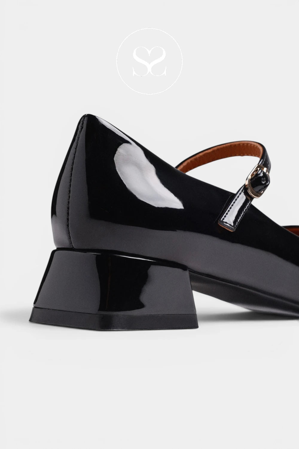 A close-up studio shot of a black patent leather Mary Jane shoe with a low block heel, showing the side profile against a light gray background.