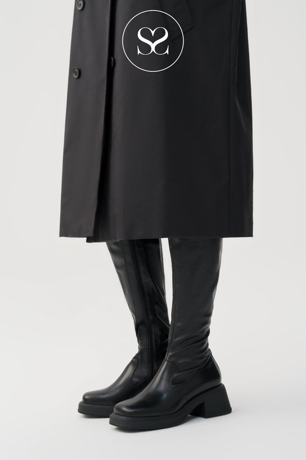 WOMAN WEARING VAGABOND BLACK LEATHER KNEE HIGH STRETCH BOOTS WITH BLACK SKIRT