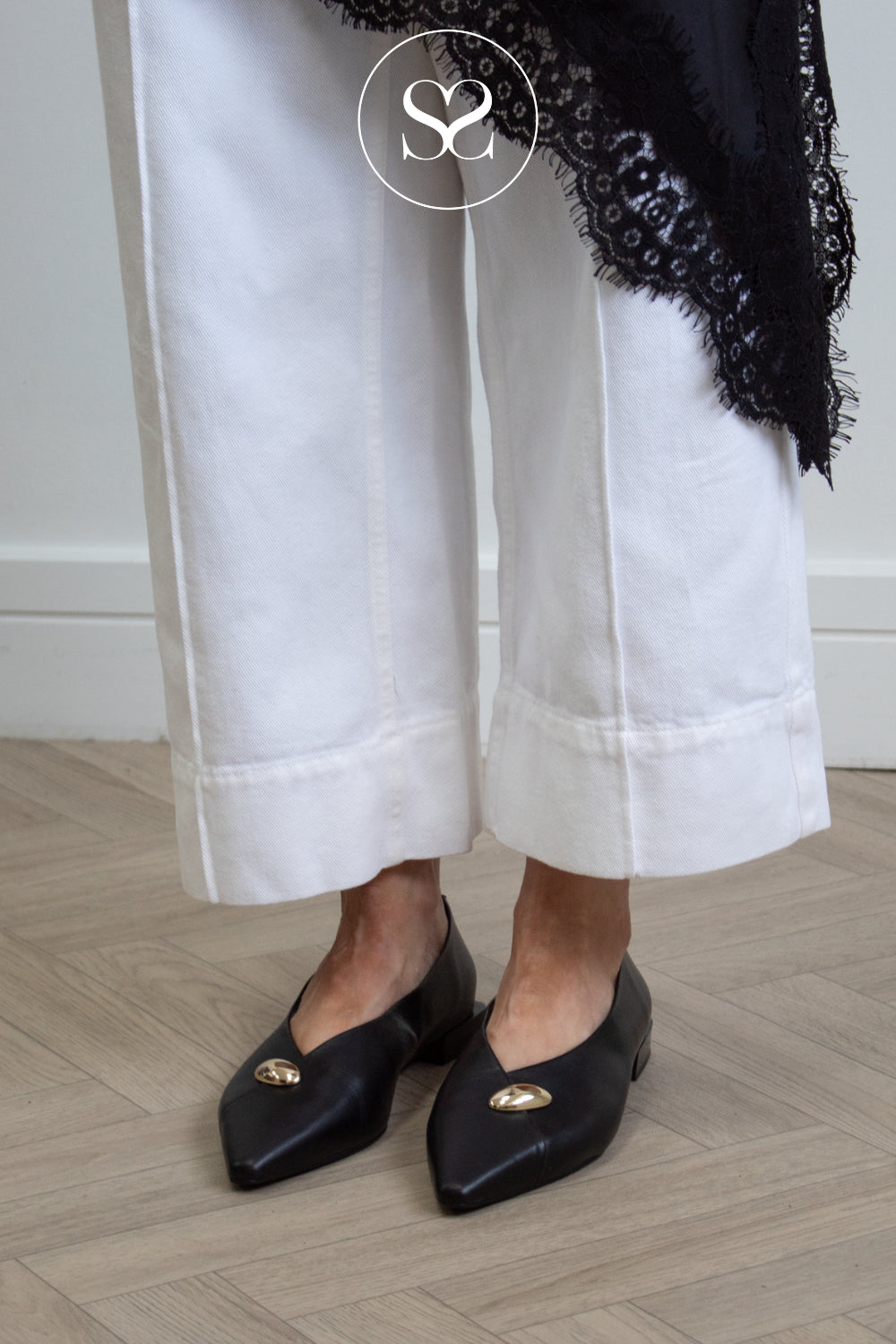woman wearing black leather poiunted toe flats with gold metal detail, elegant style from Angel Alarcon