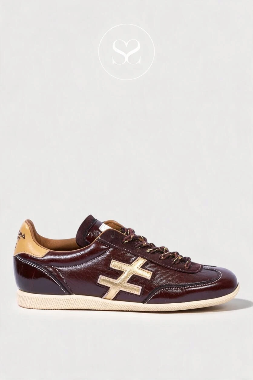 A low-top sneaker in glossy dark brown leather with a beige cross logo on the side, beige heel tab, and beige sole, shown in profile against a light gray background.