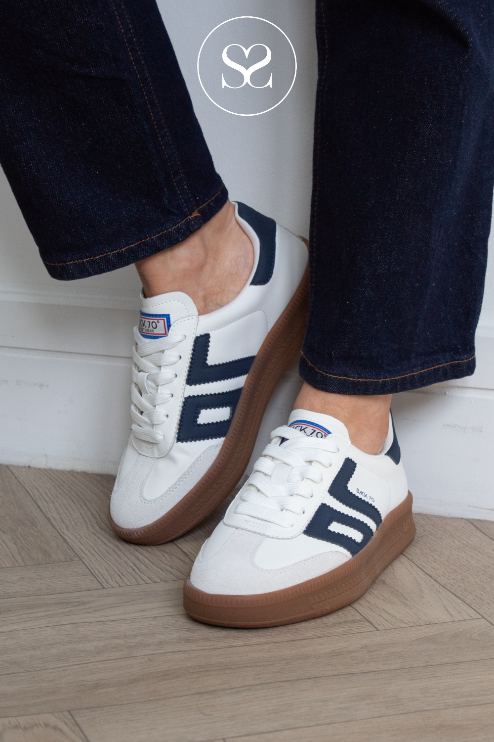 woman wearing white platfom trainers with gum sole and navy accents from back 70