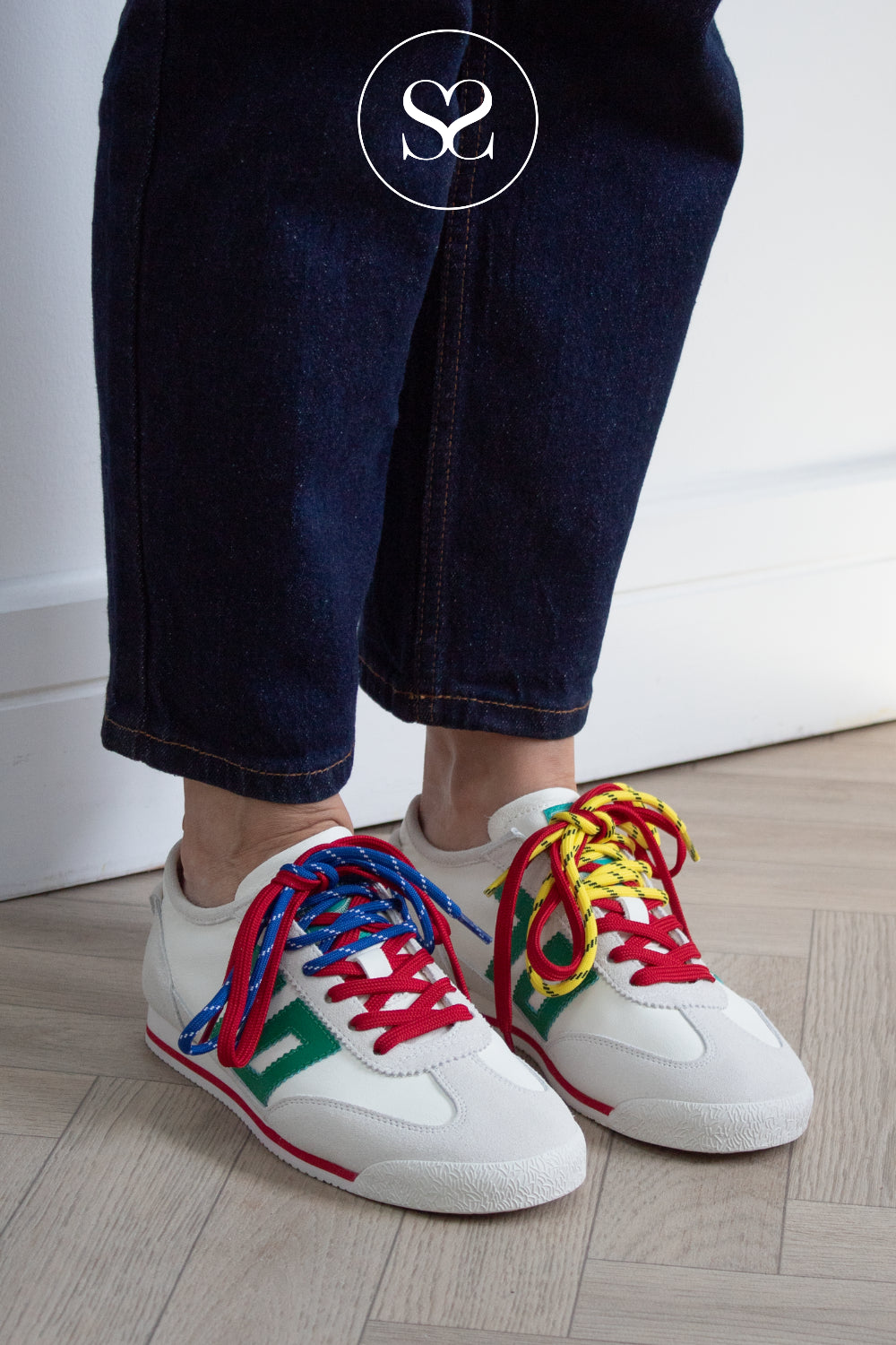 White sneakers with colorful laces worn by a woman in dark jeans on a light wooden floor. Back 70 trainers Ireland