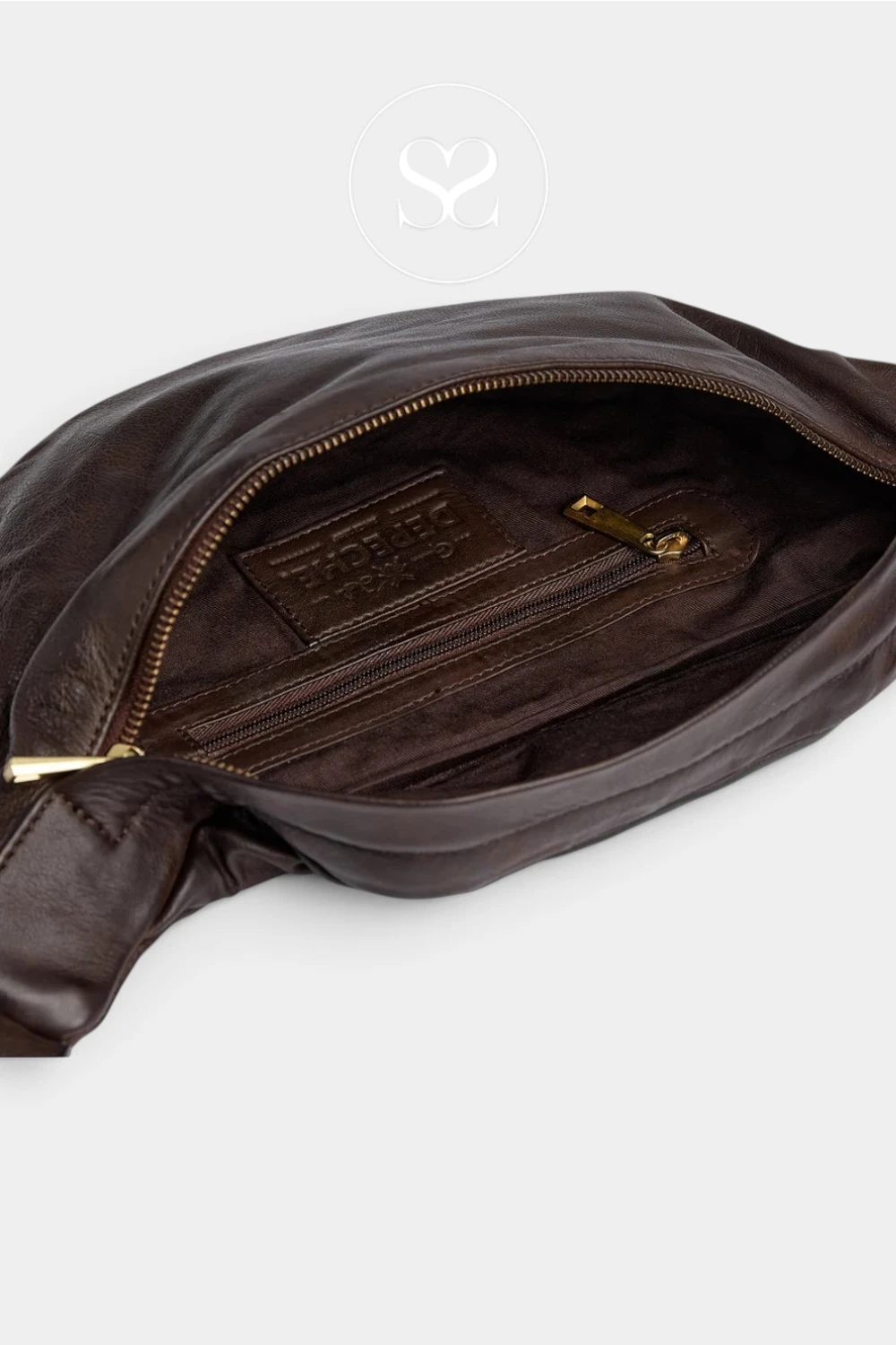 Close-up of a dark brown leather bag shown open, revealing a zippered interior, gold-tone zipper pulls, and a branded interior label. A faint circular logo watermark is visible near the top center.