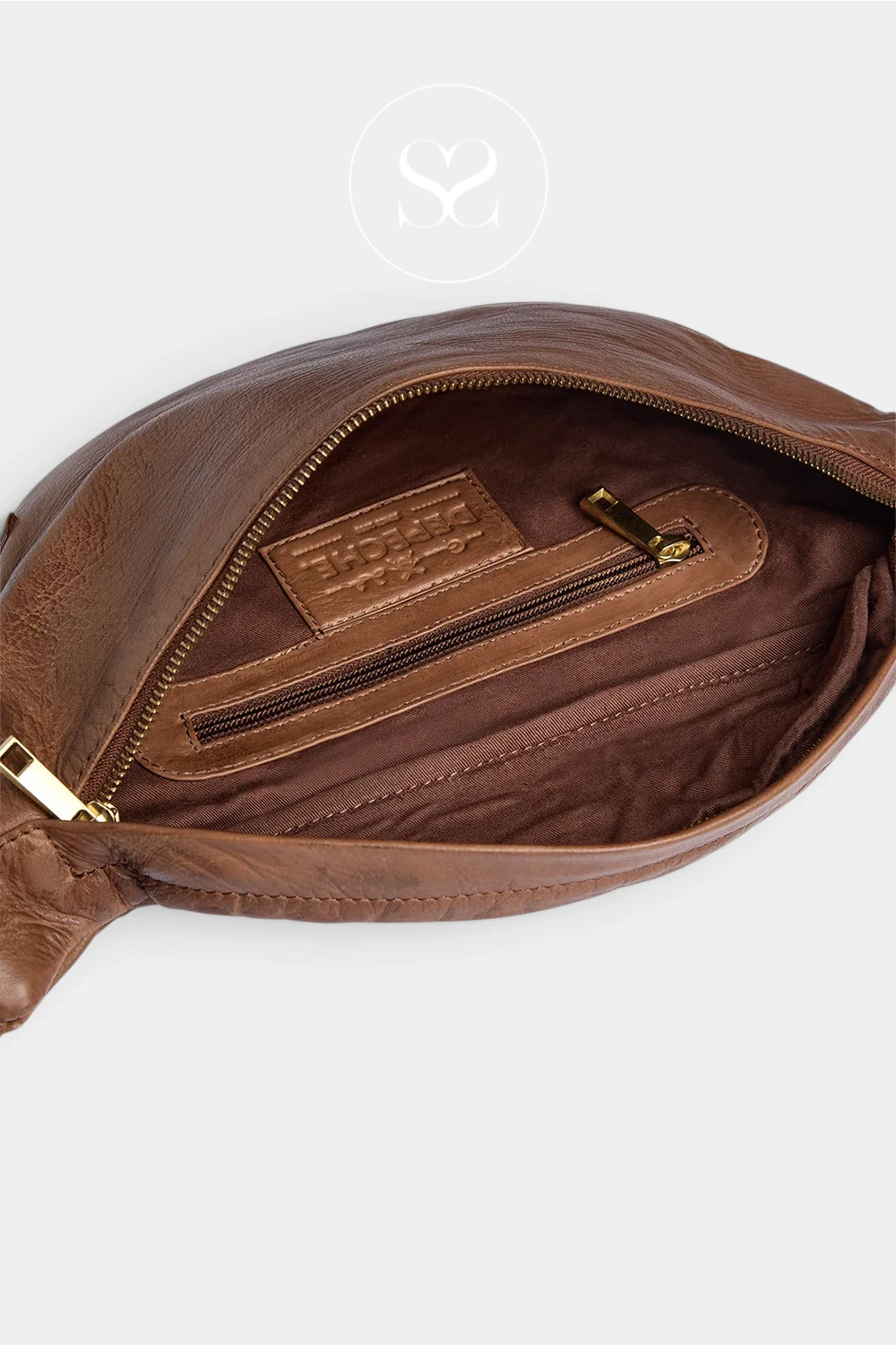 Close-up of a brown leather bag interior showing a zippered pocket with a brown leather patch and gold-tone zipper hardware, photographed on a light gray background.