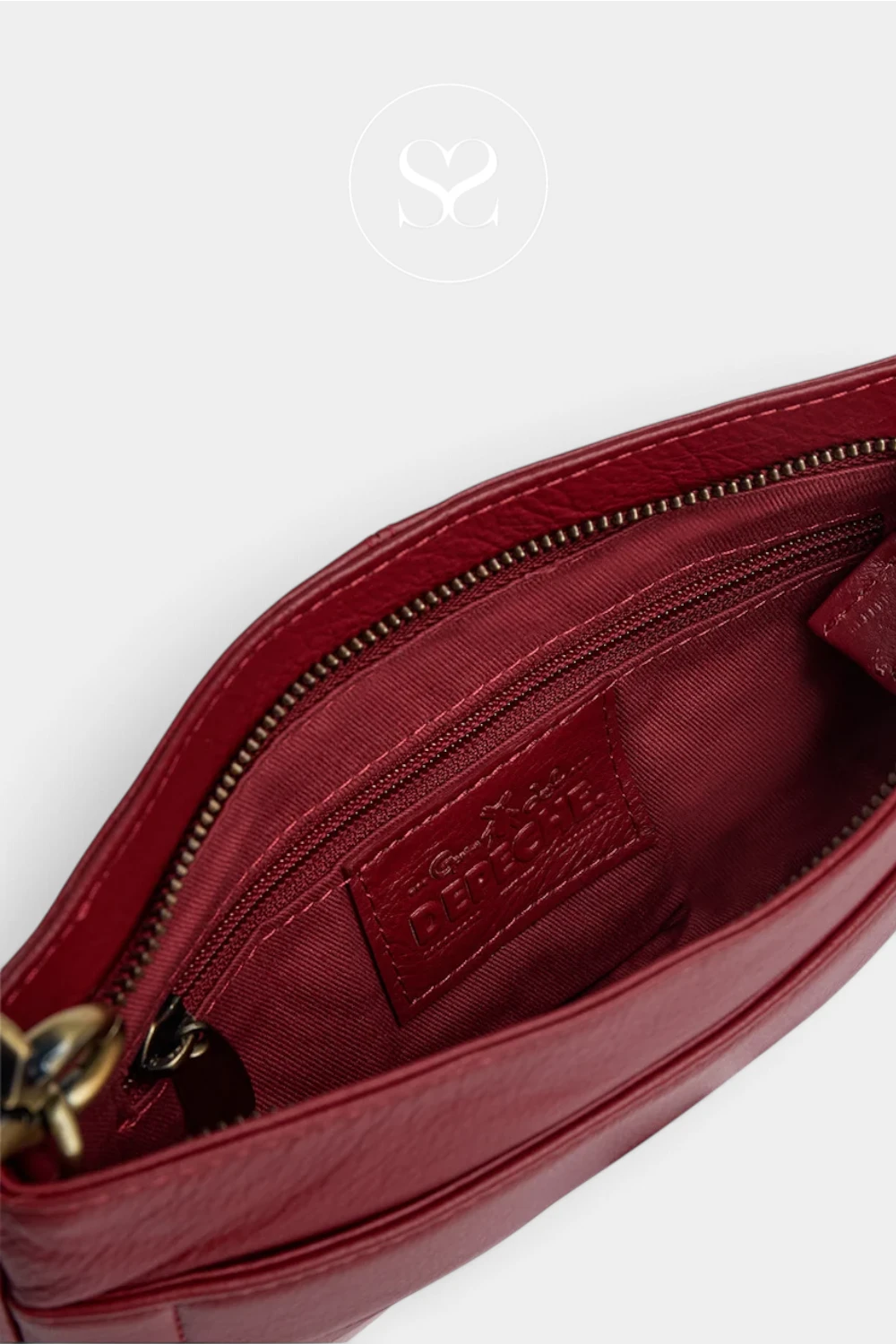 Close-up of a burgundy leather zippered pouch showing the interior lining with a debossed brand label that reads 'S.S' and 'ITALY MADE'.
