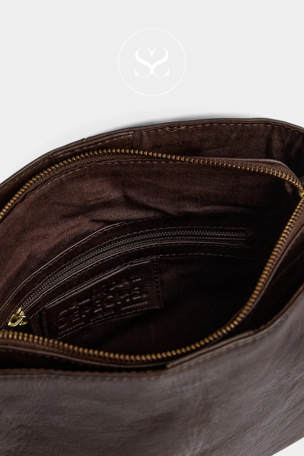 Close-up of the interior of a dark brown leather bag, showing a brown fabric lining, a zippered pocket with gold-tone zipper, and a small interior brand label.