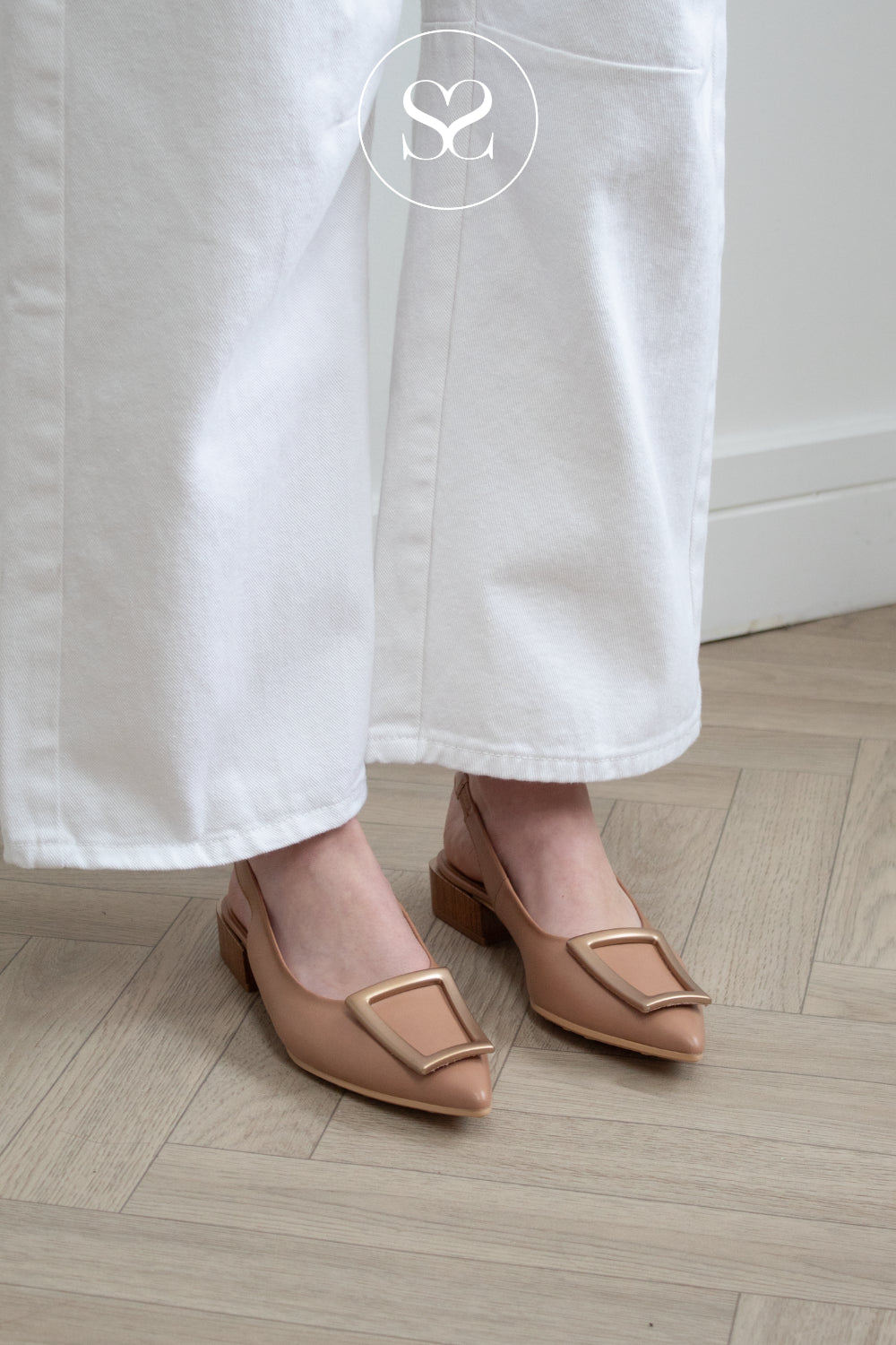 Woman wearing hispanitas camel colour pointed toe flats with brass badge detail in Ireland