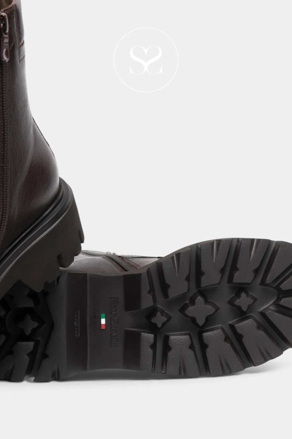 Close-up of a dark brown leather boot showing the side profile and a black lug sole with a small Italian flag detail and 'BONIA' branding, on a light gray background.