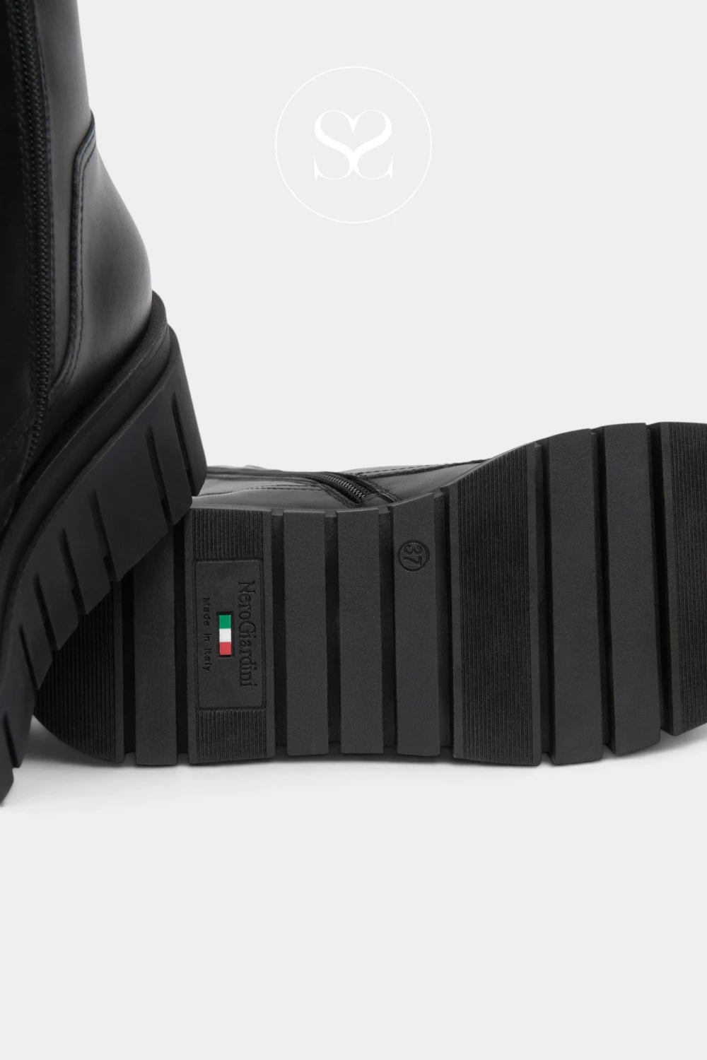 Close-up of a black leather boot showing the textured treaded sole and a small vertical brand tag with an Italian flag