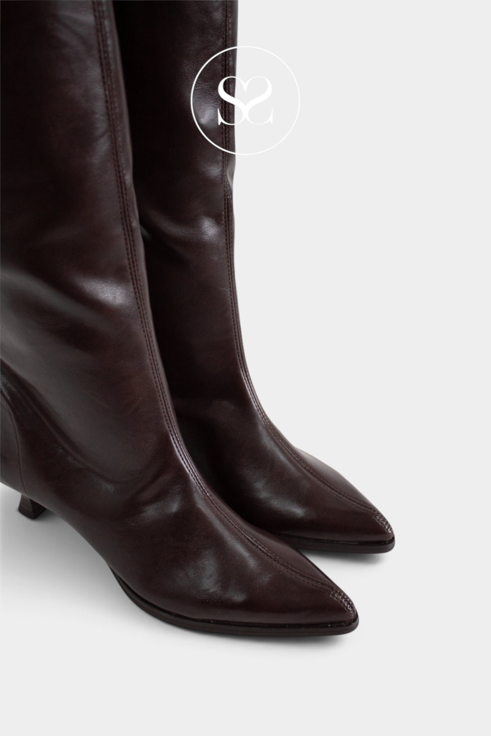 A pair of dark brown leather knee-high boots with pointed toes and low kitten heels, shown against a light grey background with a circular 'Sheneil Shoes' logo watermark near the top.