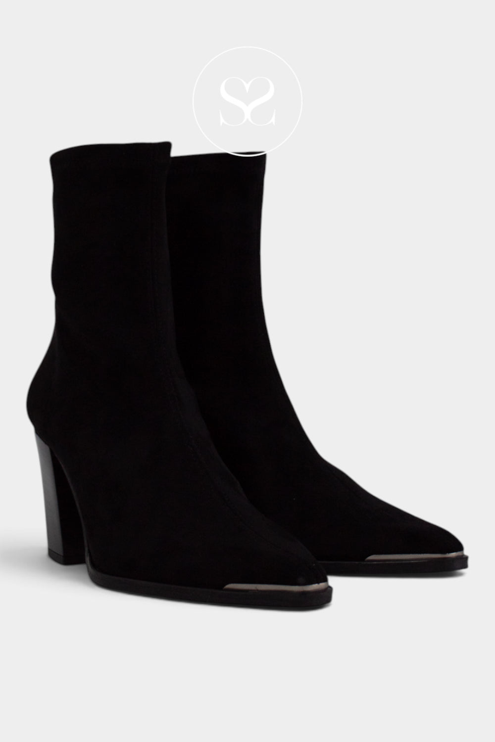 A pair of black suede ankle boots with pointed toes and block heels, shown against a light grey background.