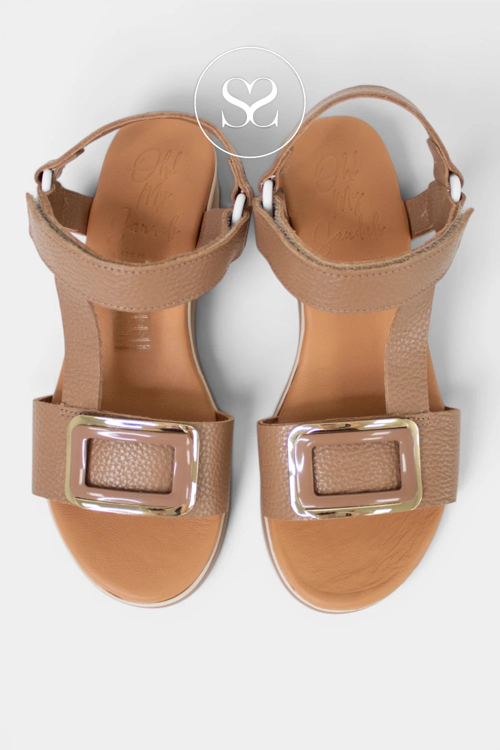 Pair of tan sandals with metallic buckles on a white background