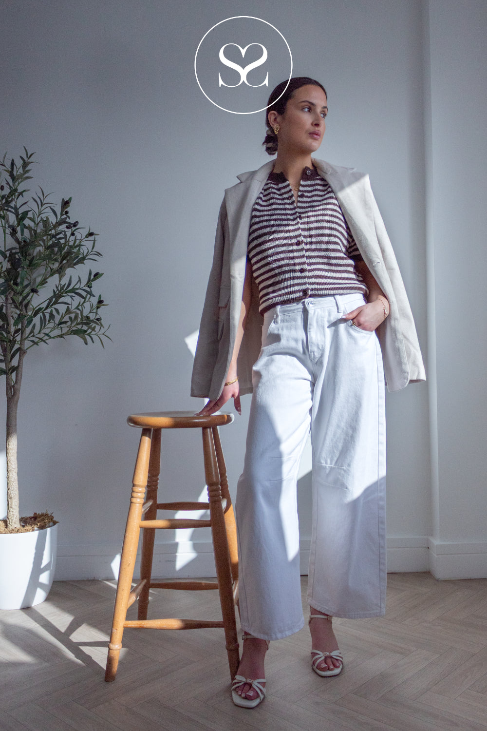 Woman in a striped shirt and white pants wearing cream lodi strappy sandals