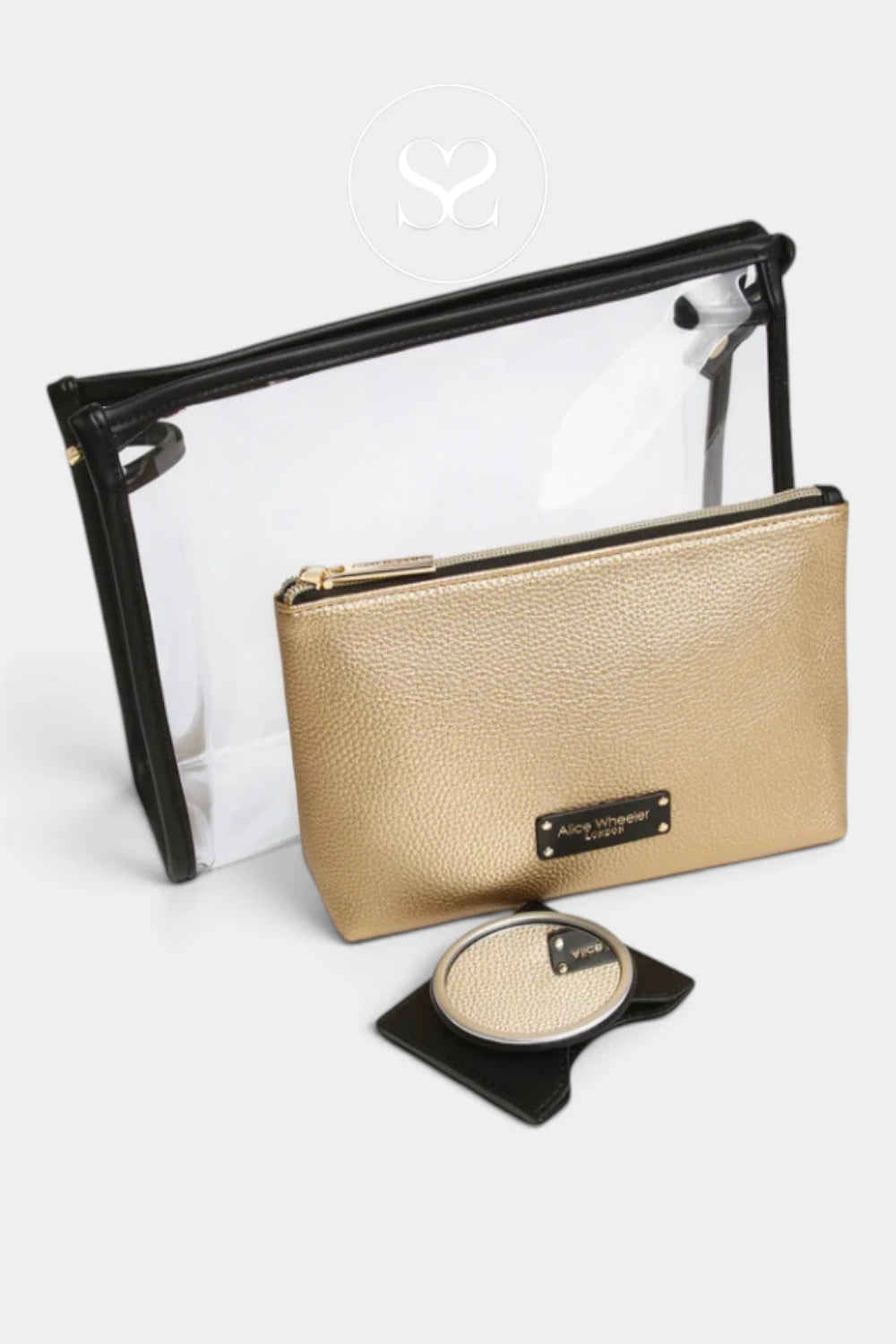 A gold pebbled leather cosmetic pouch with a black metal logo plaque, shown next to a clear zippered pouch with a black frame and a small round compact on a black stand, set against a light gray background.