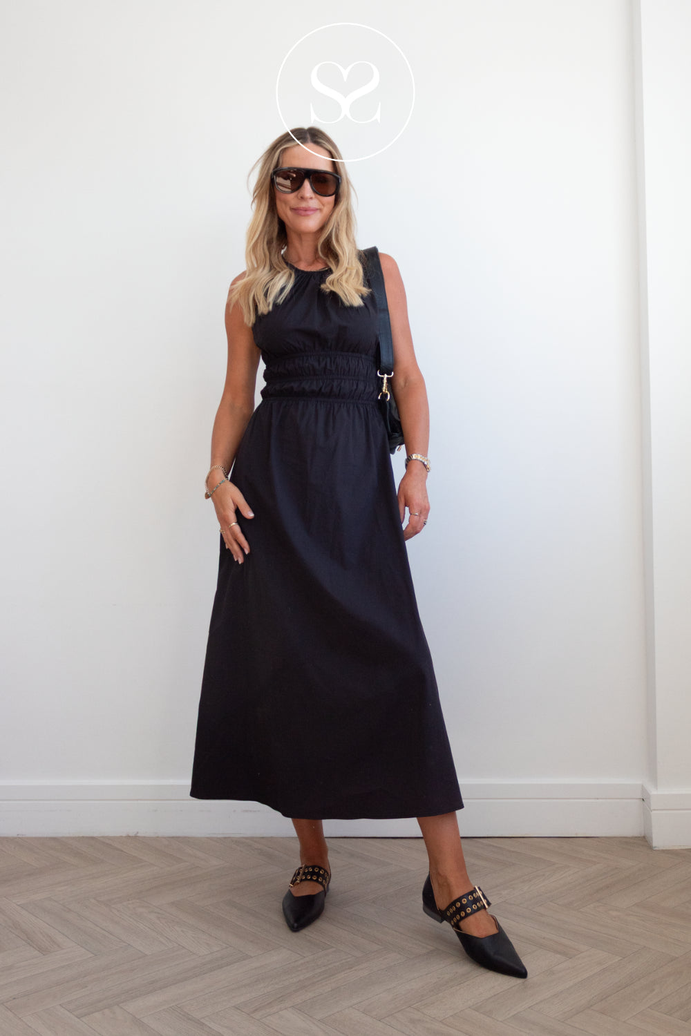 woman in edgy studded ballet flats in black leather with black bag and black oversized sunglasses