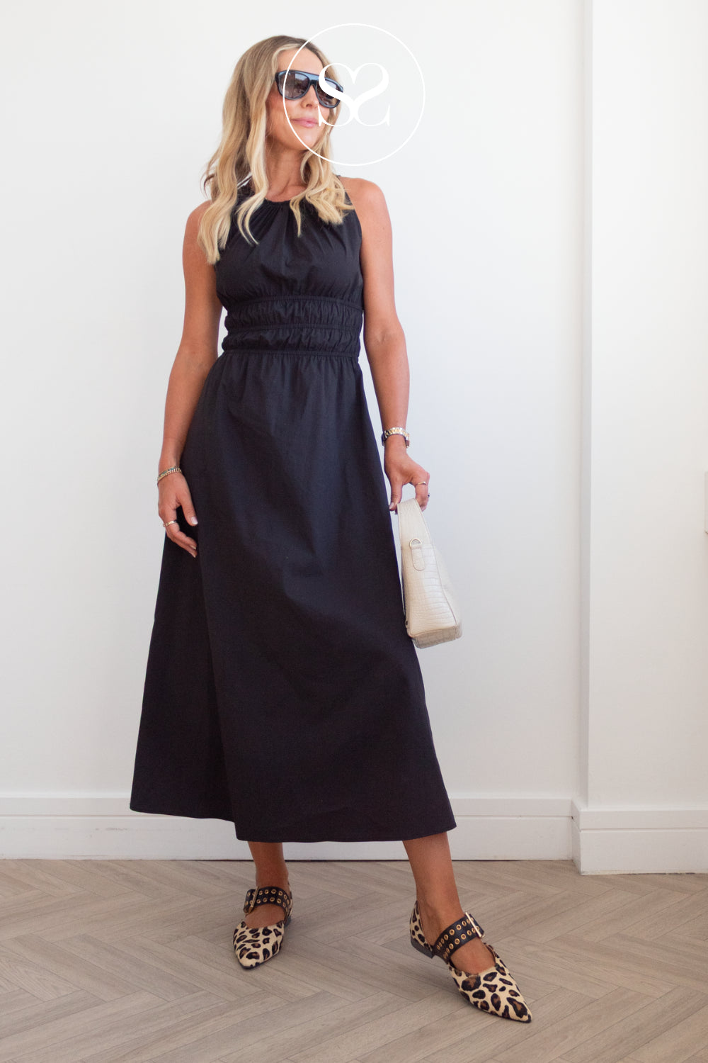 woman in black dress with pointed leopard print balley flats with cream bag and sunglasses