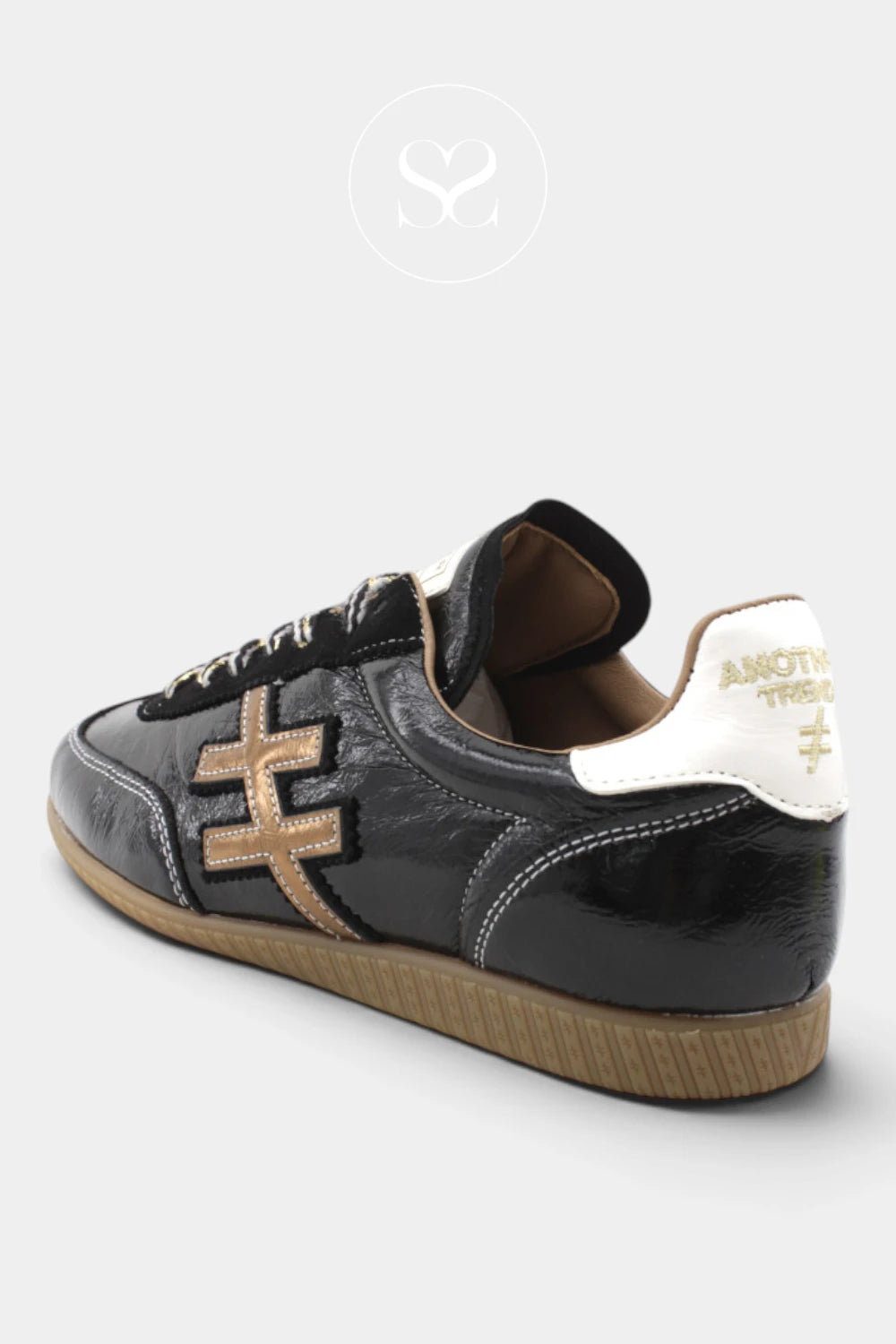 An another trend black leather sneaker with a gold geometric side logo, a white heel tab with gold lettering, and a brown gum sole, shown from a three-quarters angle on a light gray background.