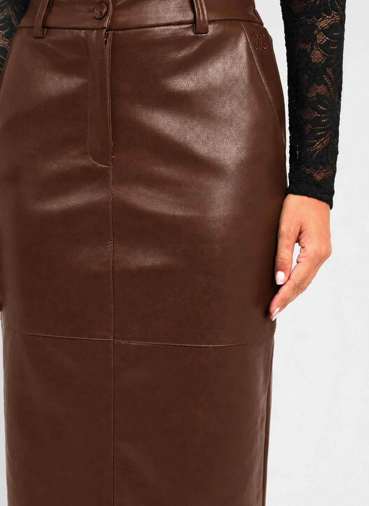 A close-up of a brown faux-leather pencil skirt worn by a model, paired with a black lace long-sleeve top, against a plain white background.