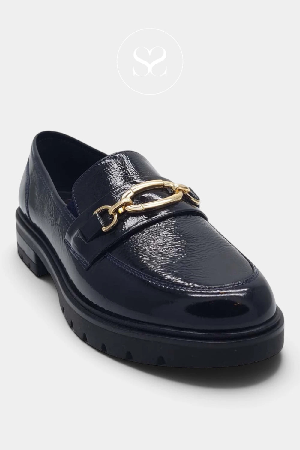 A dark navy blue patent leather loafer with a chunky black sole and a prominent gold-tone chain link detail across the vamp, shown on a light gray background.