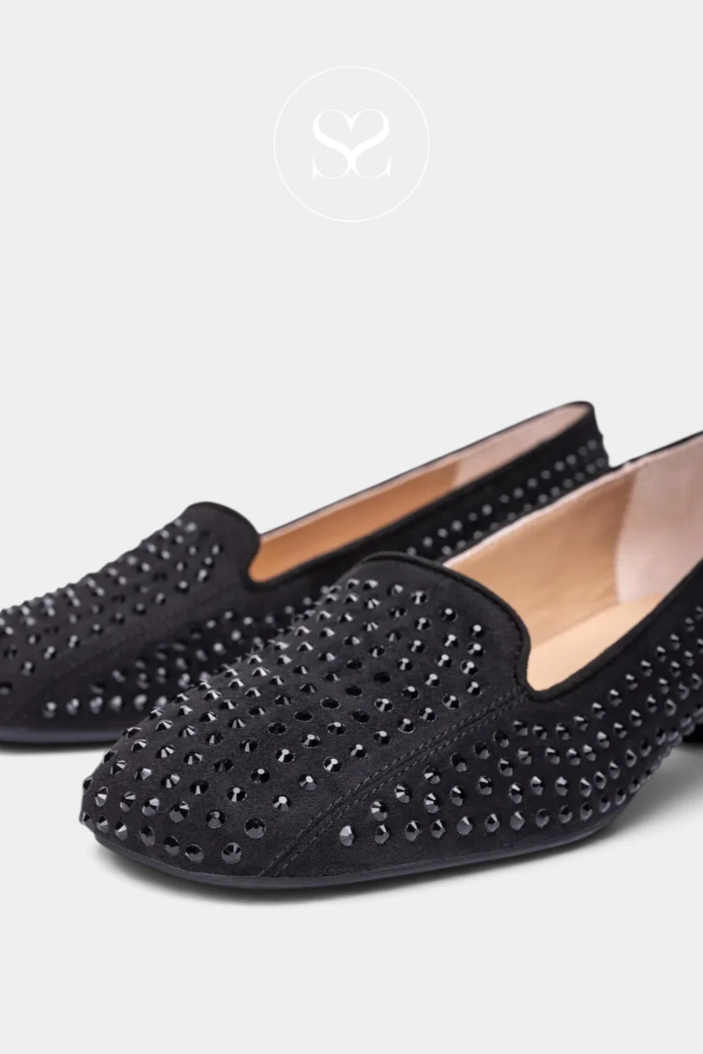 A pair of black slip-on flats embellished with silver studs, shown on a light gray background with a faint brand logo at the top.