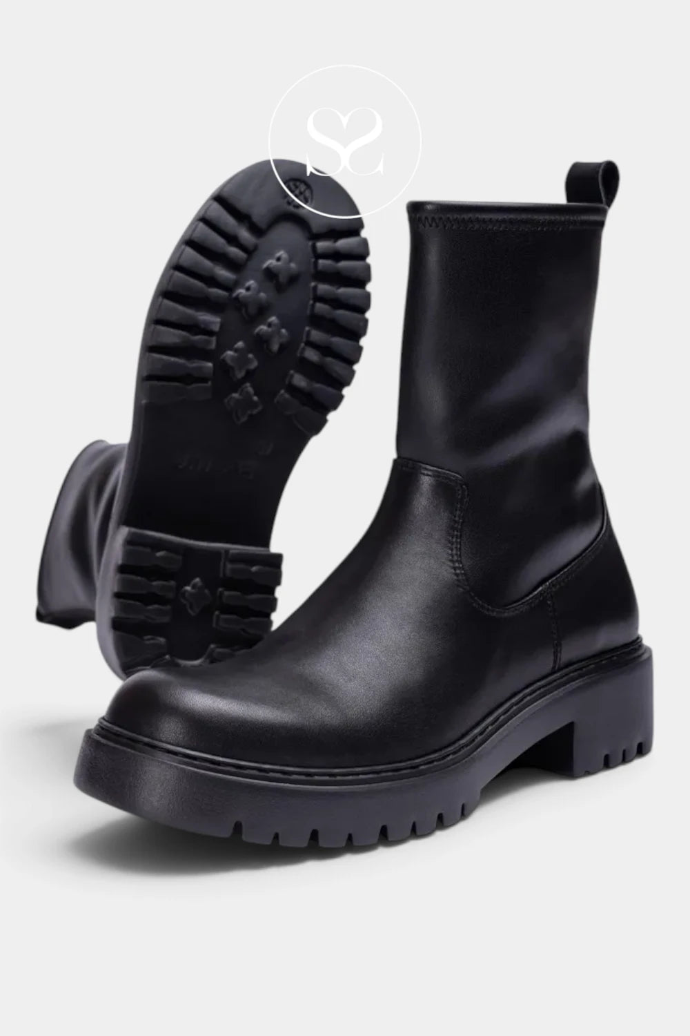 A pair of black leather Chelsea-style ankle boots with chunky lug soles, shown on a light gray background with one boot standing upright and the other angled to display the treaded outsole.
