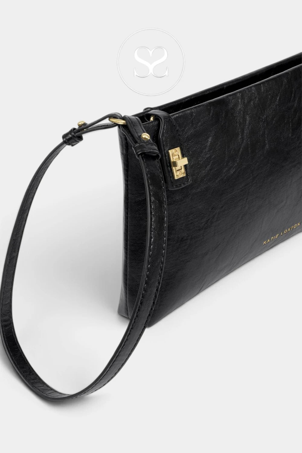 A black textured leather clutch bag with a gold cross-shaped turn-lock clasp and a matching black leather wristlet strap, shown on a light gray background.
