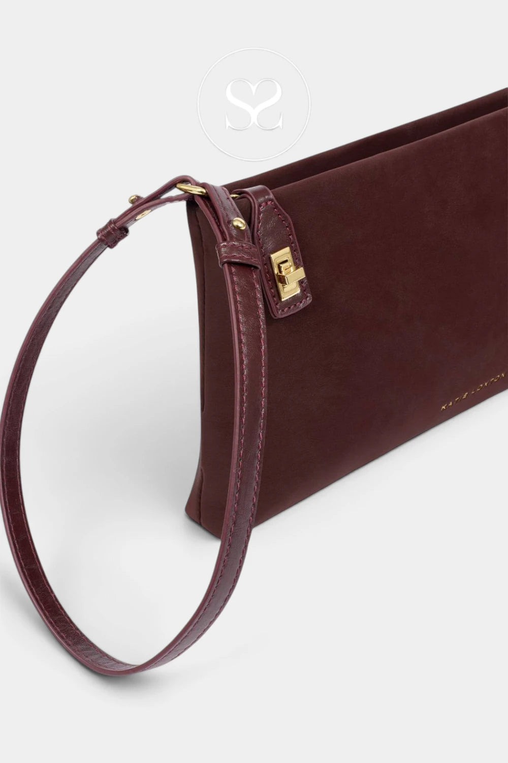 A dark burgundy leather clutch bag with a matching wristlet strap and gold-tone hardware, shown on a light gray background.