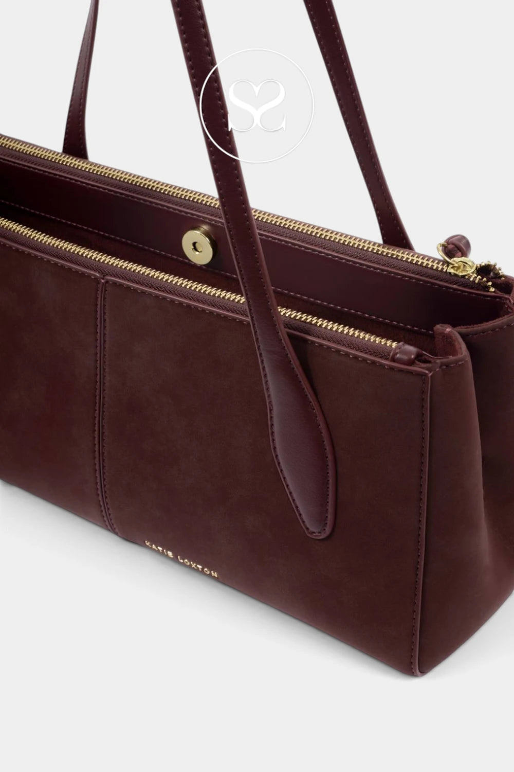 A close-up of a dark brown leather handbag with gold-tone hardware, including a zipper, snap button, and a small gold brand plaque near the bottom.