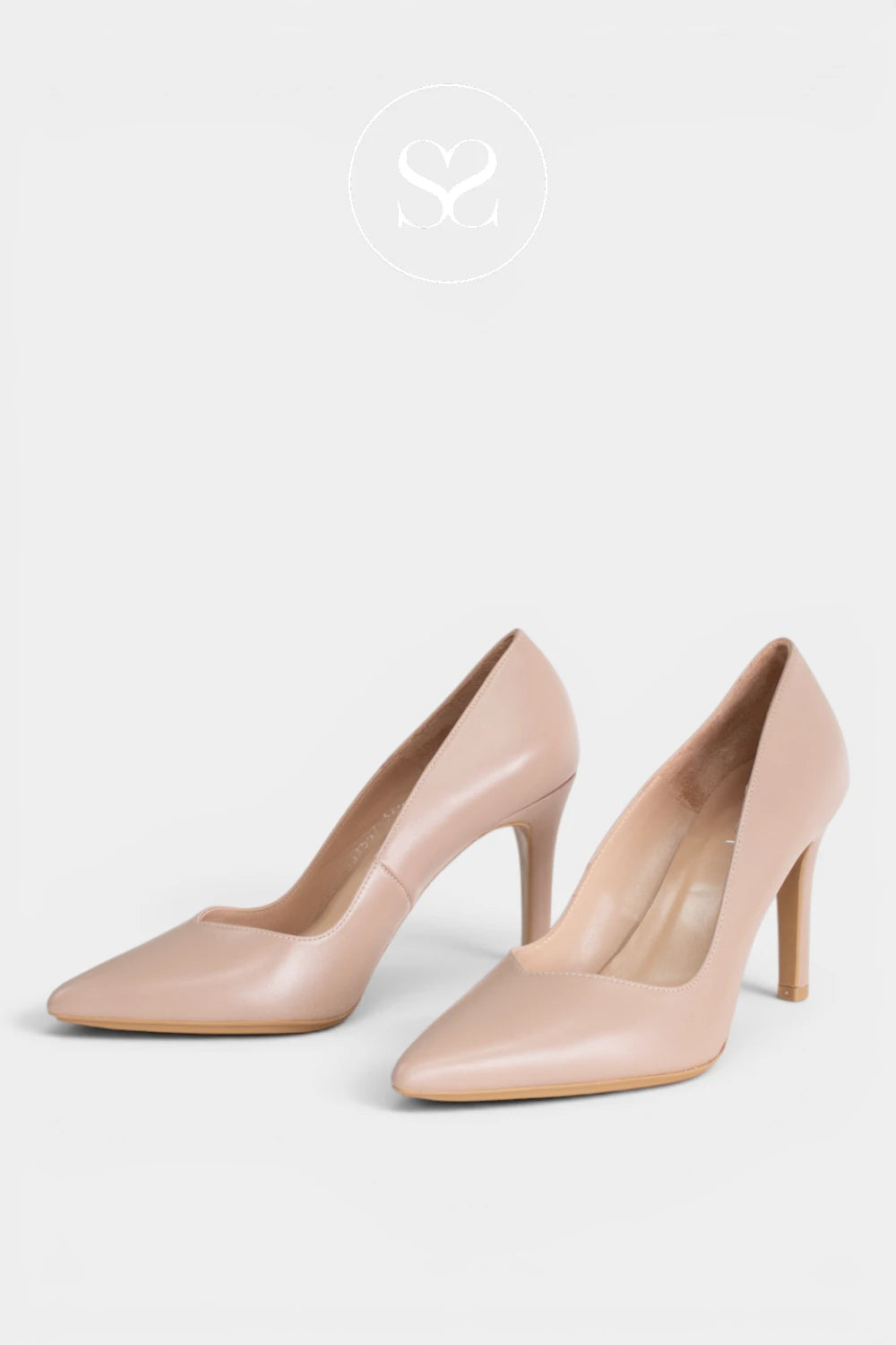 A pair of pointed-toe high heels in a light nude pink color, displayed on a clean light gray background with a faint brand logo at the top.