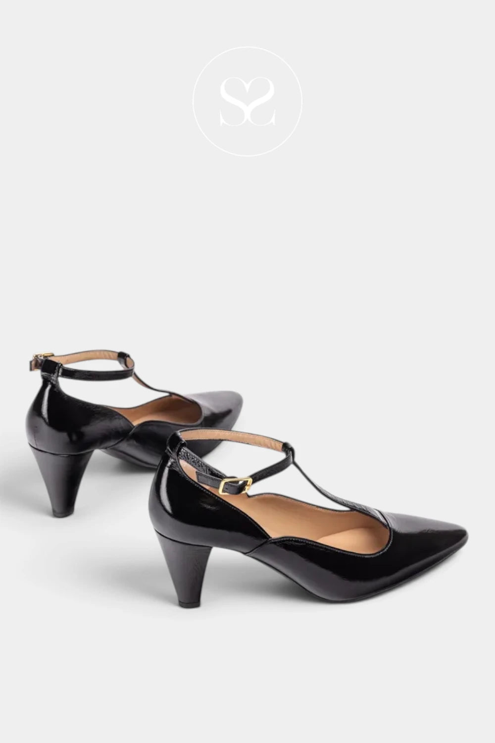 A pair of black patent leather T-strap high heels with pointed toes and low block heels, displayed on a light gray background with a faint logo watermark at the top.