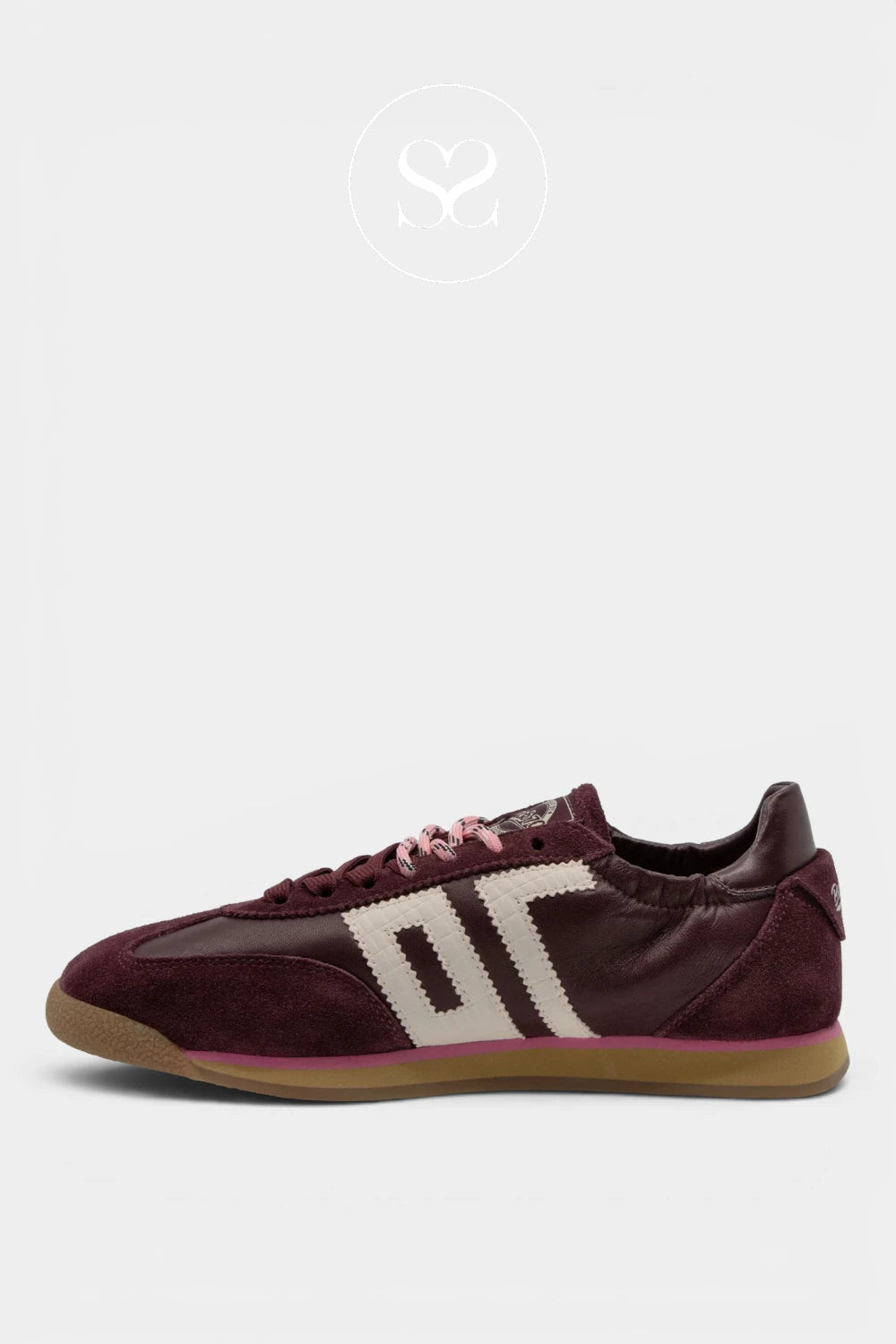A low-top sneaker in burgundy suede and leather with a cream-colored side stripe design, pink laces, and a gum sole, shown against a light gray background.