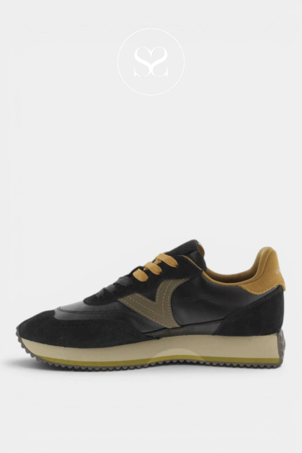 A low-top sneaker in black suede and leather with tan accents on the side, tongue, and heel, set against a light gray background.