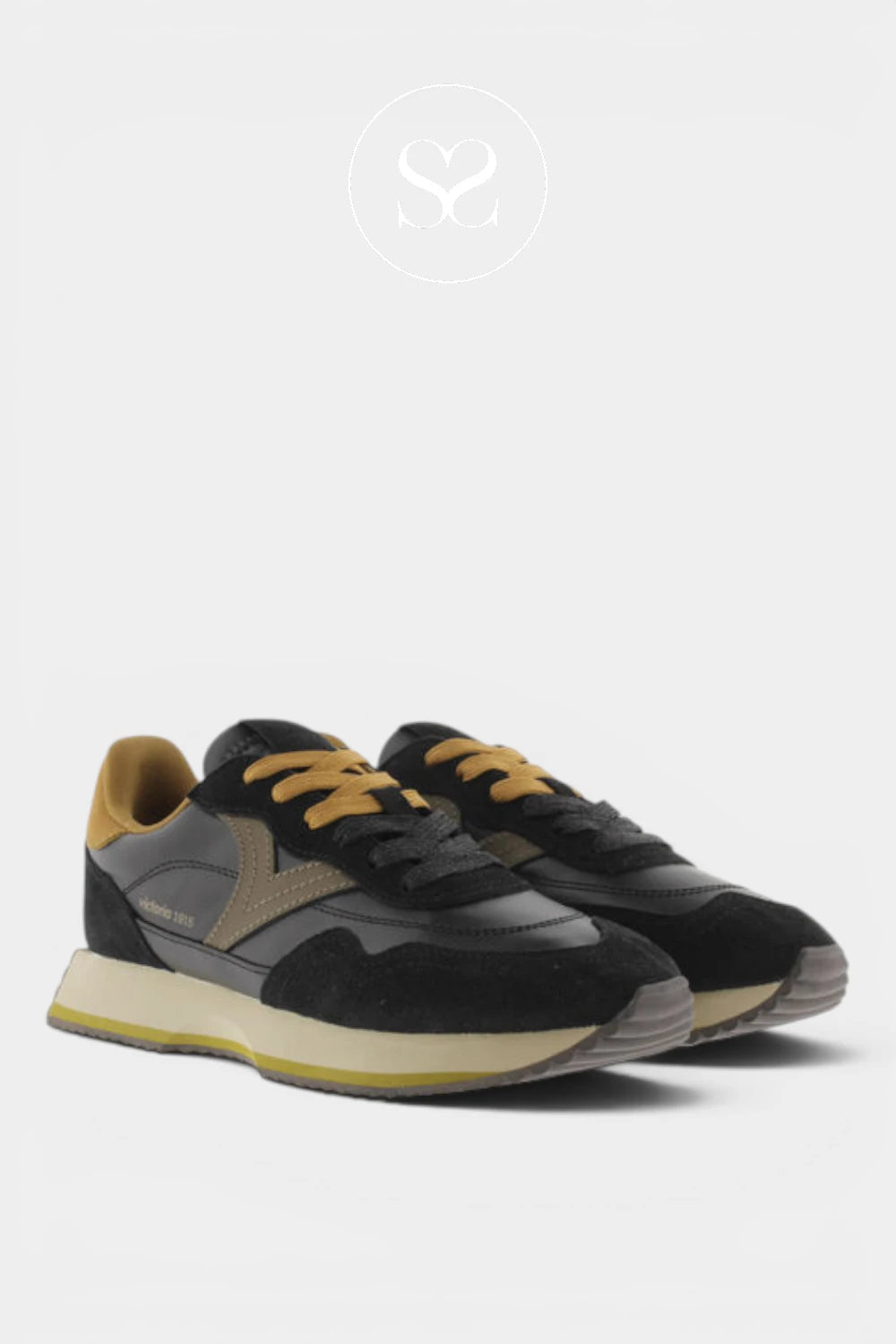A pair of low-top sneakers in black suede and leather with tan accents, black laces, and a chunky cream and tan sole, shown on a light gray background.